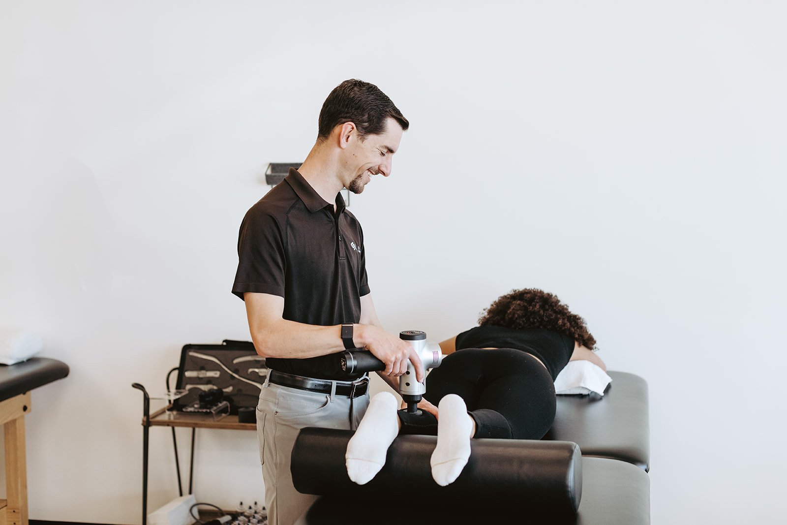 Physical therapist using a massage gun during a physical therapy appointment.