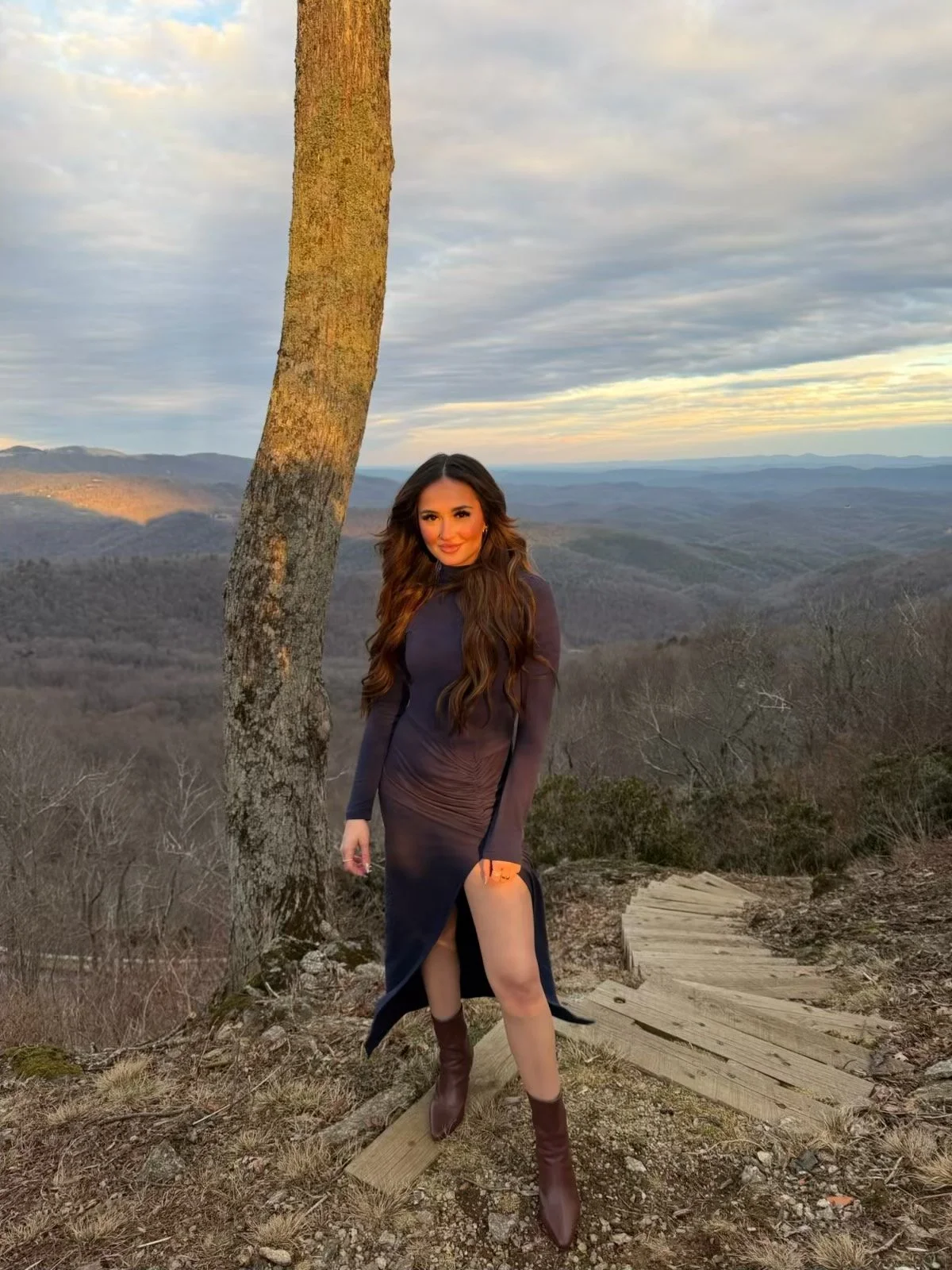 Madison is a stylist at Harlow. She is brunette, wearing a navy dress and boots.