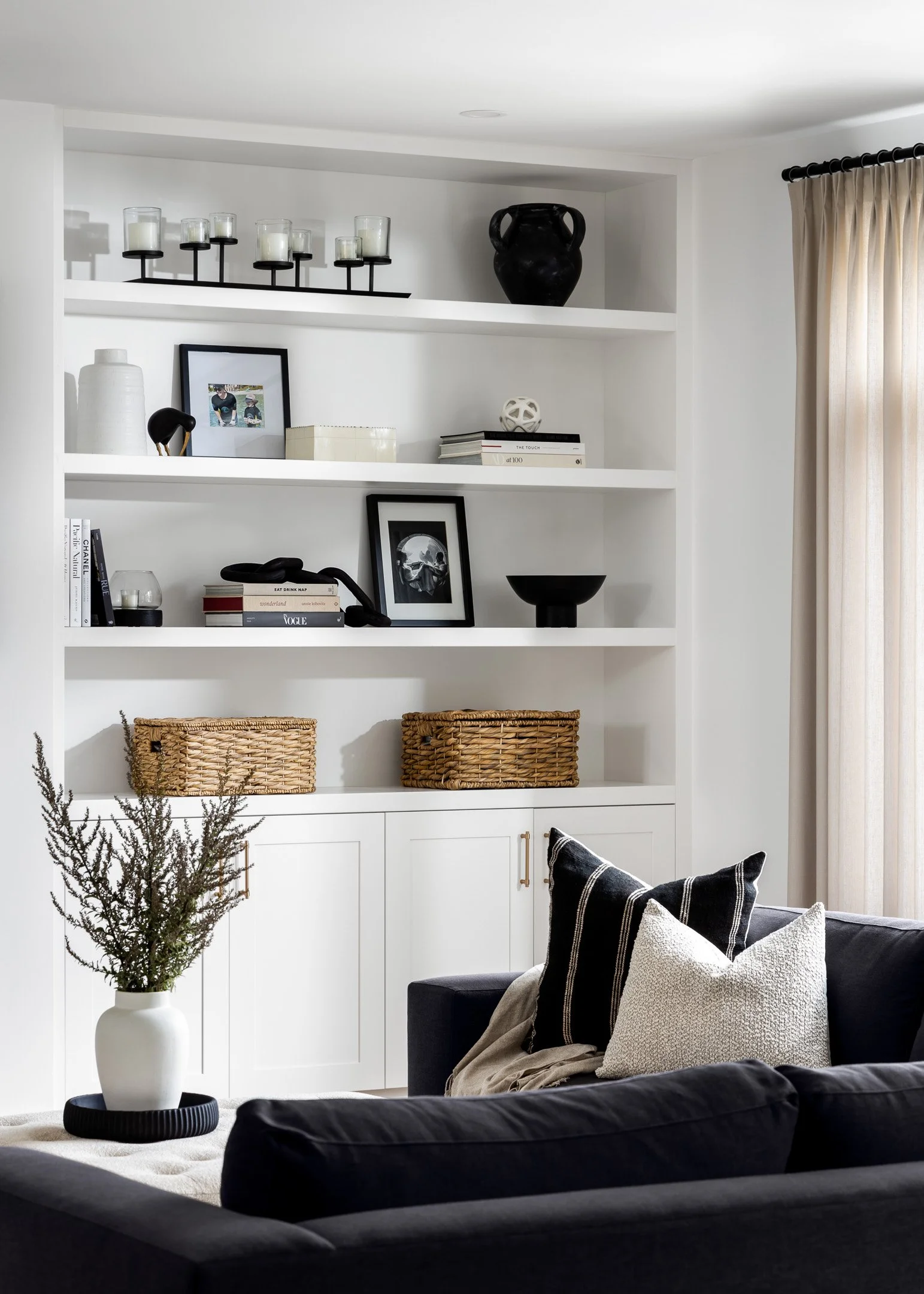 Modern designed living room with charcoal sectional and white custom cabinetry with open shelves by Studio Moffatt, London, Ontario