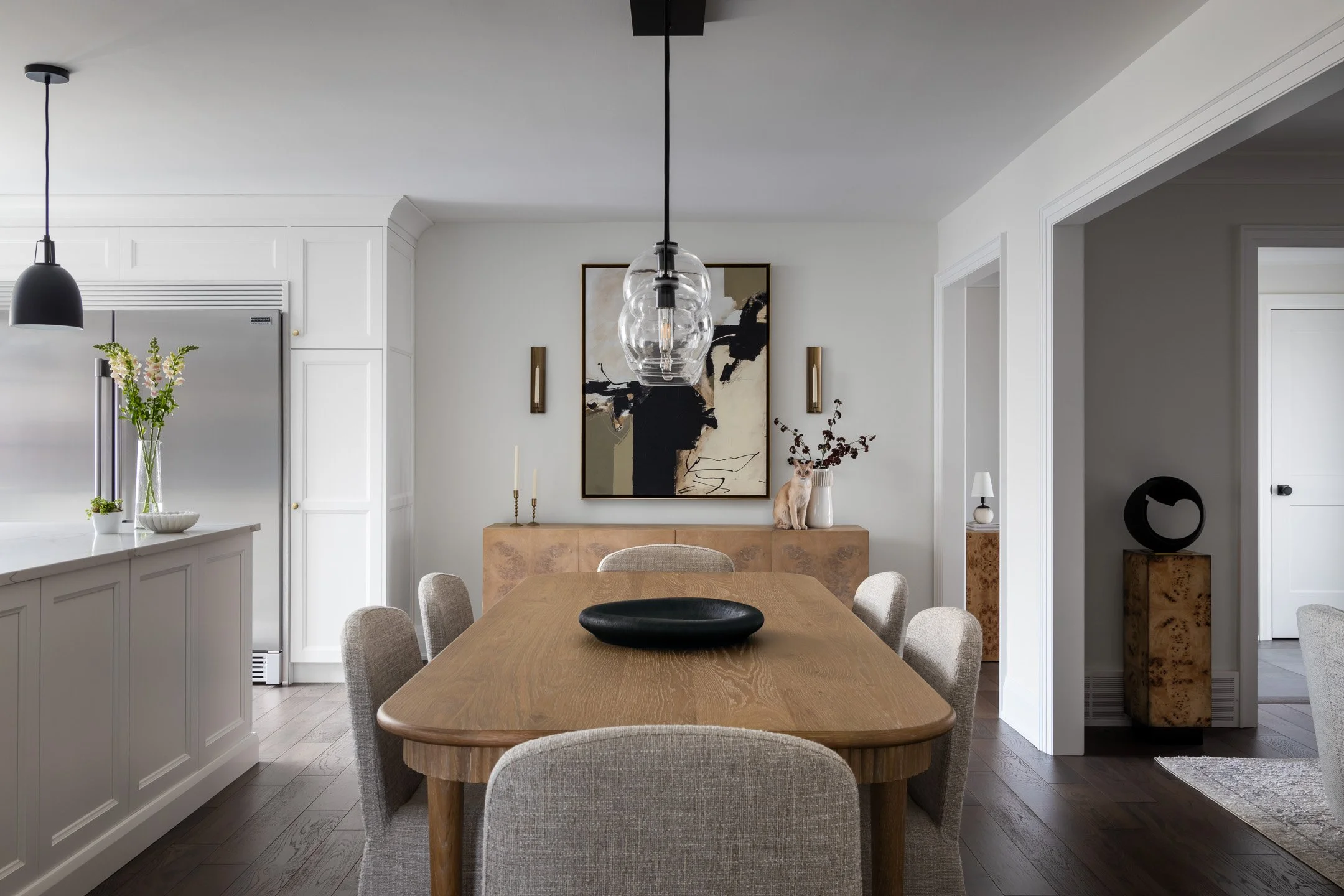 Elegant dining room featuring oak table, textured upholstered dining chairs and abstract artwork by Studio Moffatt in London, Ontario