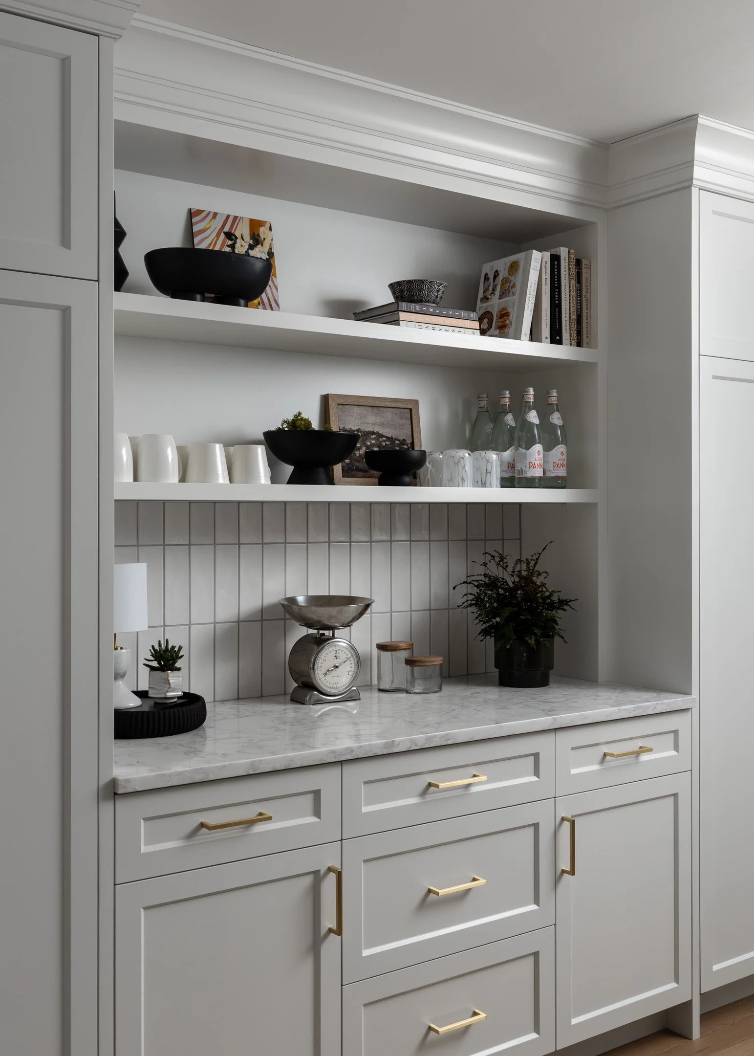 Kitchen remodeled with custom white cabinetry, open shelves, brass hardware and quartz countertop by Studio Moffatt in London, Ontario