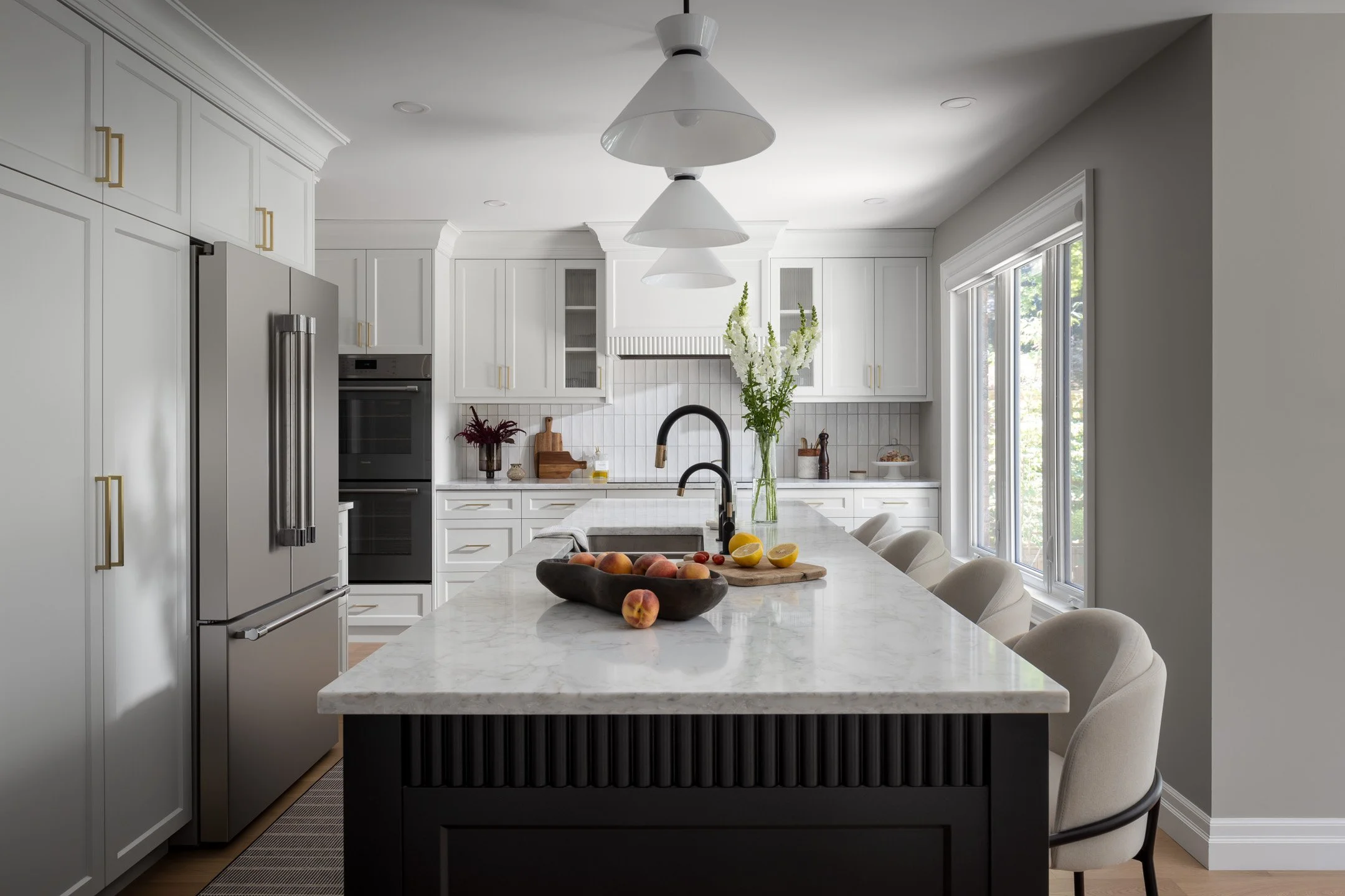 Residential renovation featuring a kitchen remodel with custom white cabinetry, a black kitchen island, custom range hood and quartz countertops.  Interior Design project by Studio Moffatt in London, Ontario