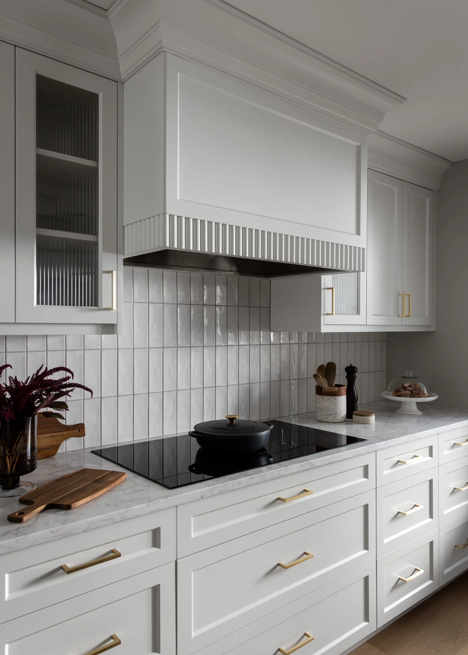 Residential renovation with custom kitchen design featuring white cabinetry, brass hardware, custom range hood by Studio Moffatt in London, Ontario