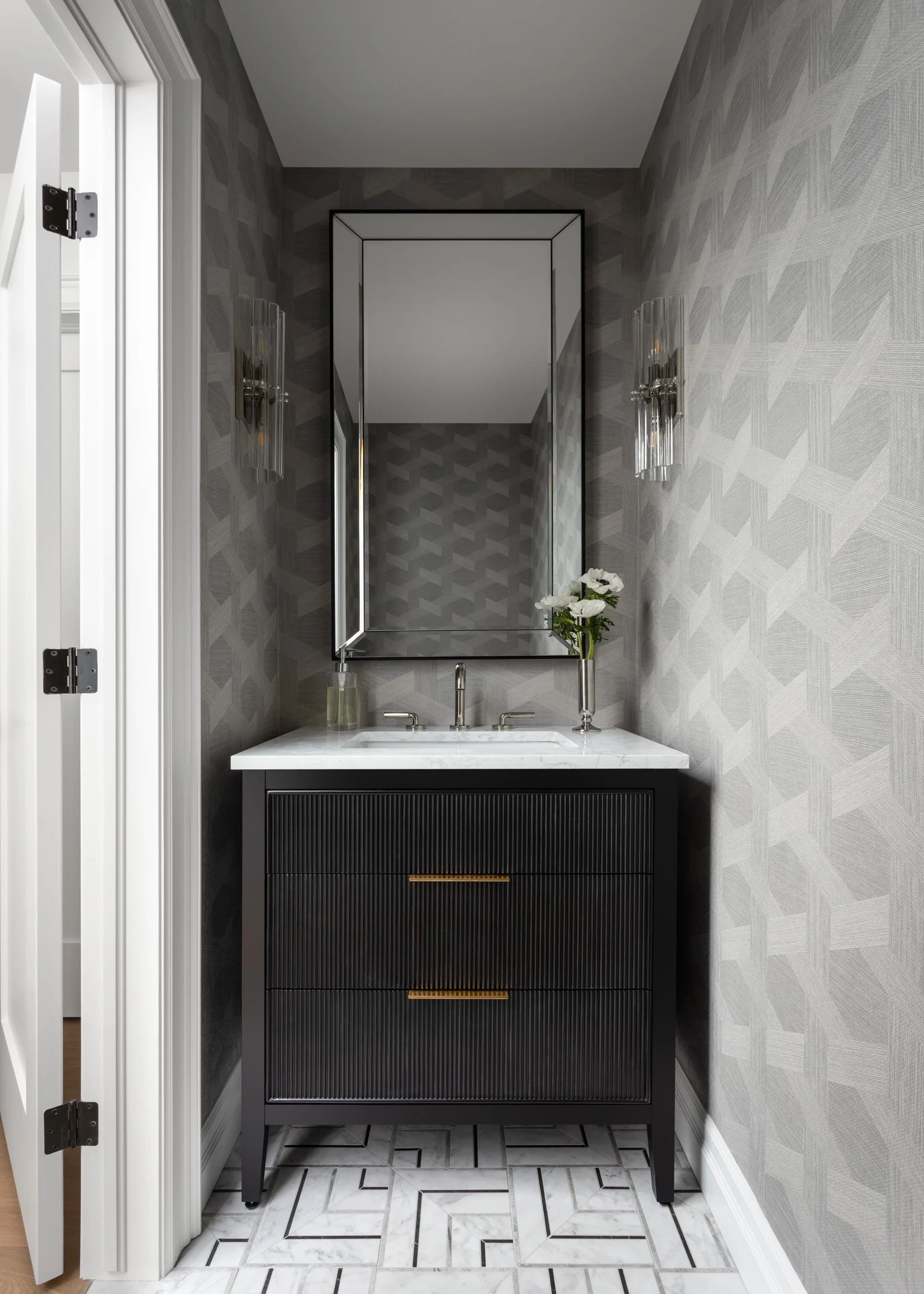 Remodeled neutral powder room with black vanity, geometric wallpaper and La Marca mosaic tile flooring by Studio Moffatt in London, Ontario
