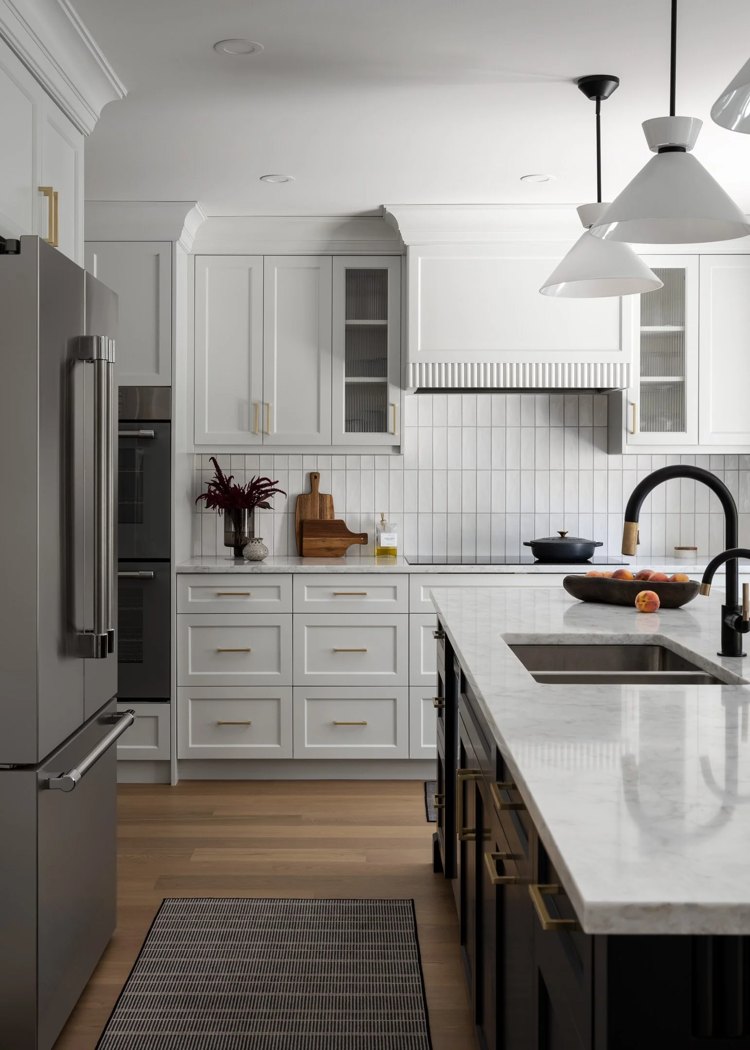 Modern kitchen featuring white oak flooring, white and black custom cabinets and quartz countertops by Studio Moffatt in London, Ontario