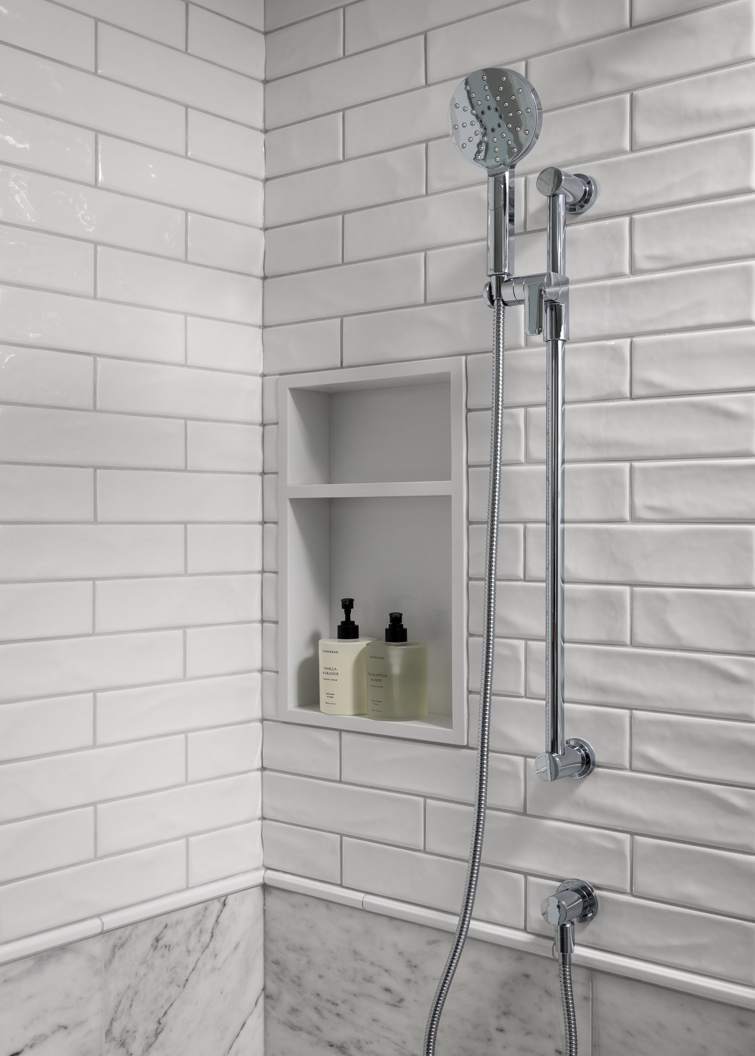 Timeless and elegant primary ensuite renovation featuring a combination of marble wall tile and a subway tile, a white quartz shower niche and polished chrome fixtures by Studio Moffatt