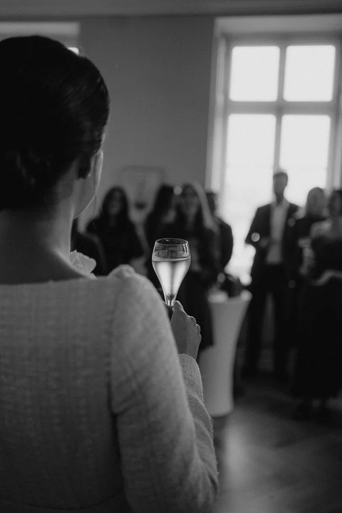 Hochzeitsreportage in Bonn die Braut hält ein Sektglas während einer emotionalen Rede, aufgenommen in zeitloser Schwarz-Weiß-Ästhetik.