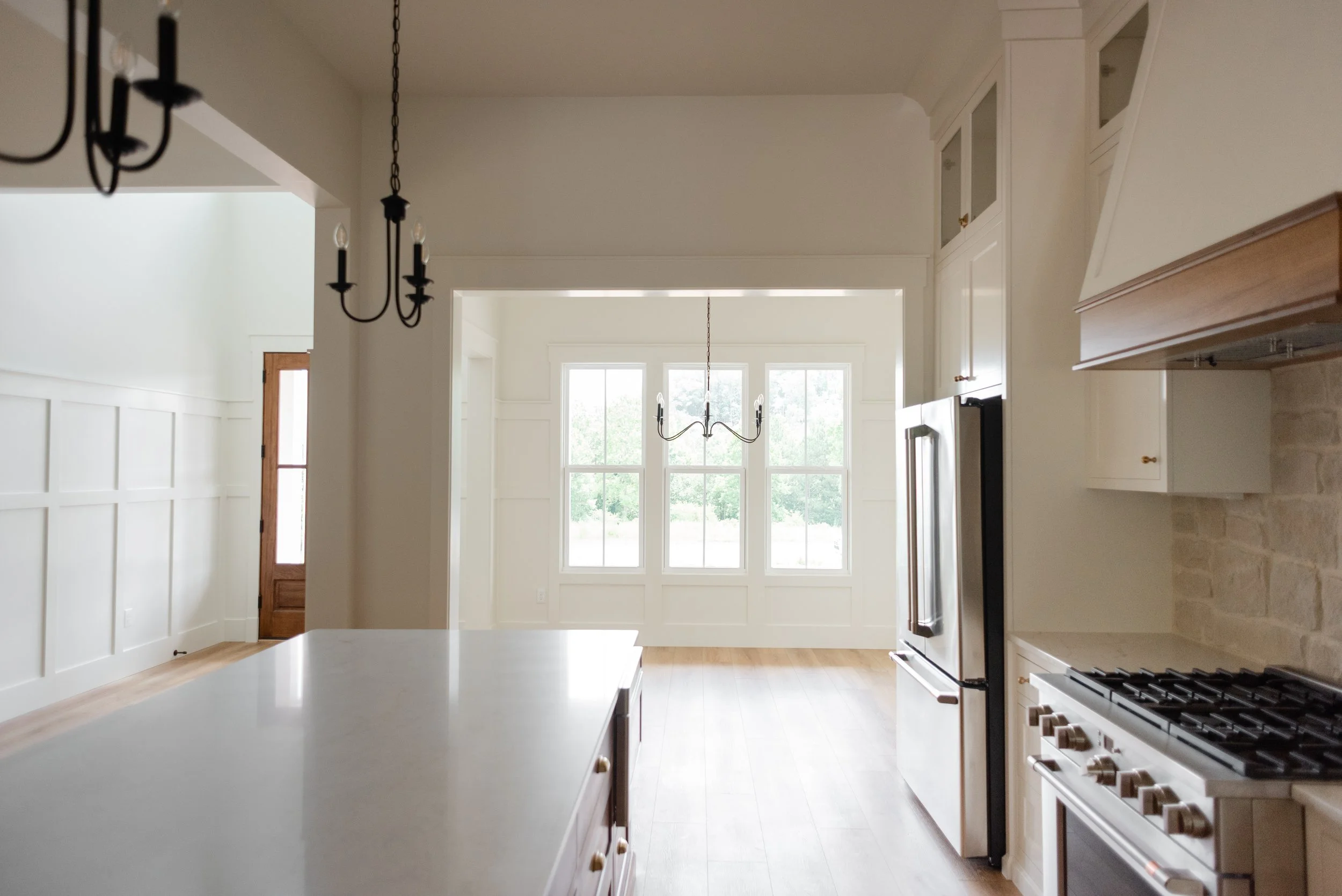 Bright custom kitchen and dining area by Knoxville custom home builder Wiersma Homes, with white cabinets, wooden countertops, stainless appliances, and large windows for natural light.