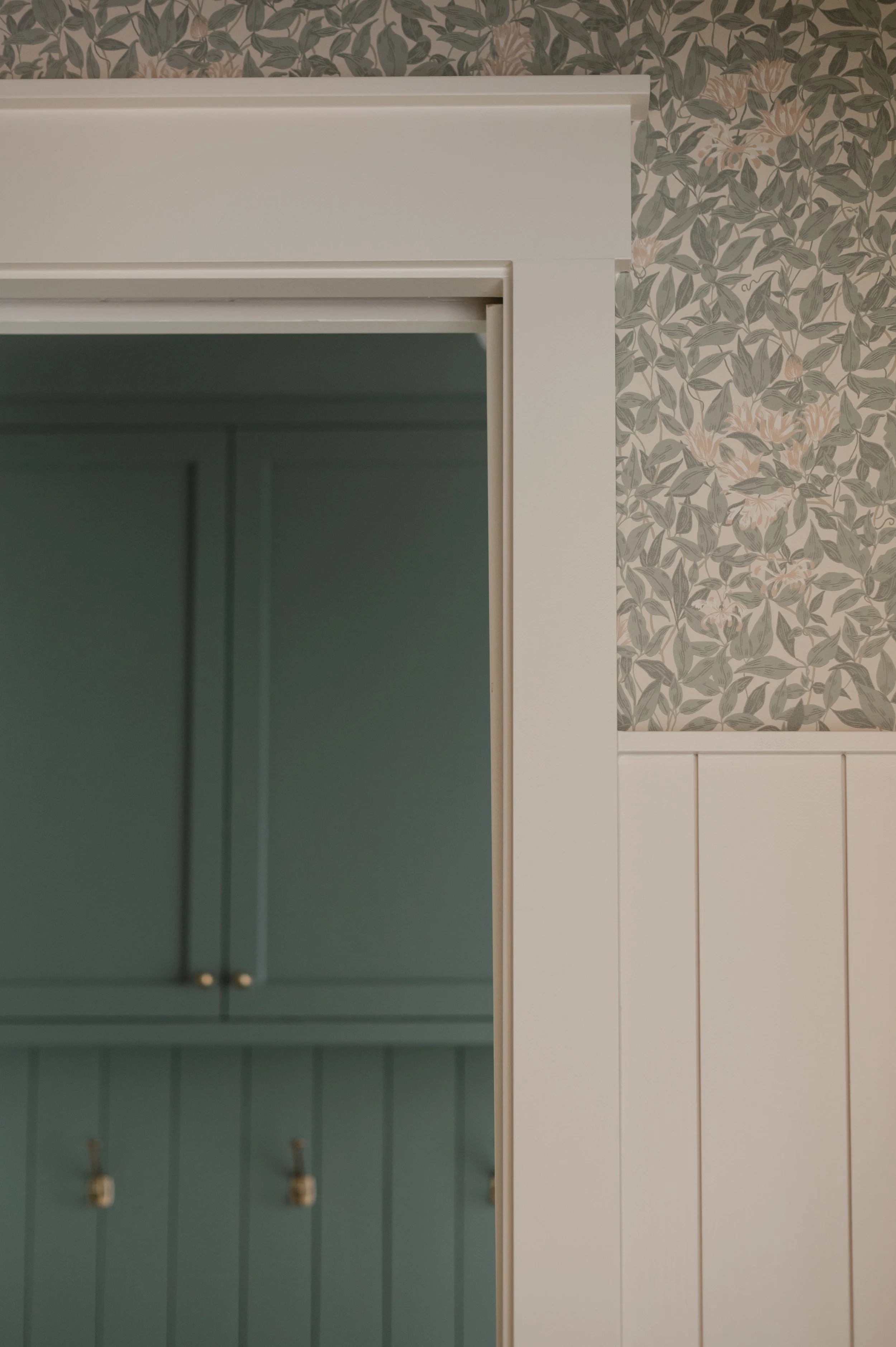 Interior doorway detail in a custom luxury home by Knoxville custom home builder Wiersma Homes, featuring floral wallpaper, beadboard wainscoting, and timeless natural design elements.