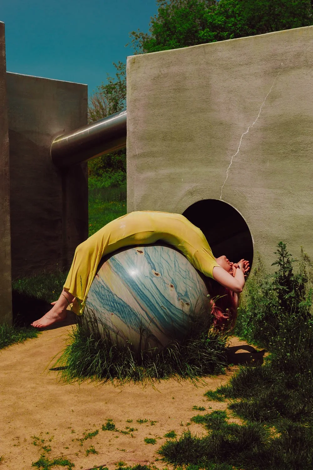 A photo of NYC Kinky Redhead Escort Julia Flowerbomb wearing a yellow dress, laying on a sculpture.