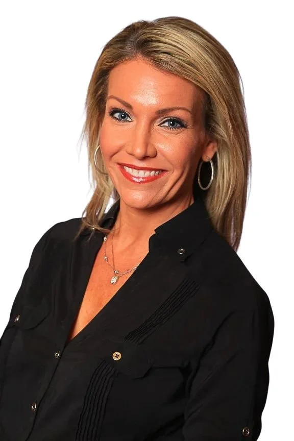Headshot photographer - A woman with blonde hair and blue eyes smiling, wearing a black shirt with silver buttons, hoop earrings, and a necklace, against a light purple background.