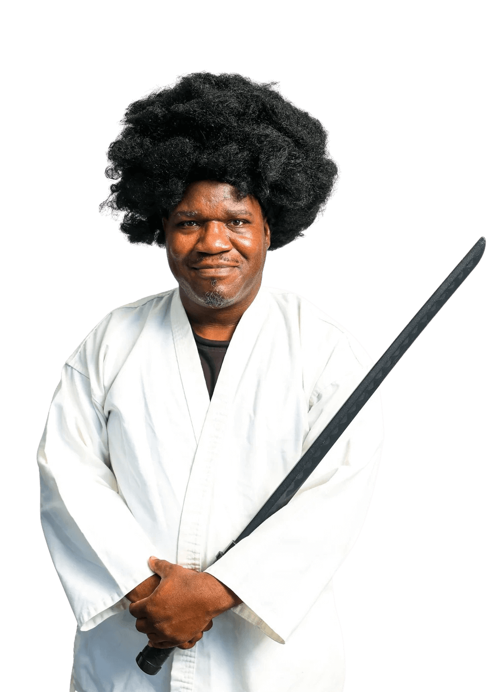 Man dressed as a martial arts character, wearing a white kimono and holding a black sword, with a large afro hairstyle, standing against a black background.
