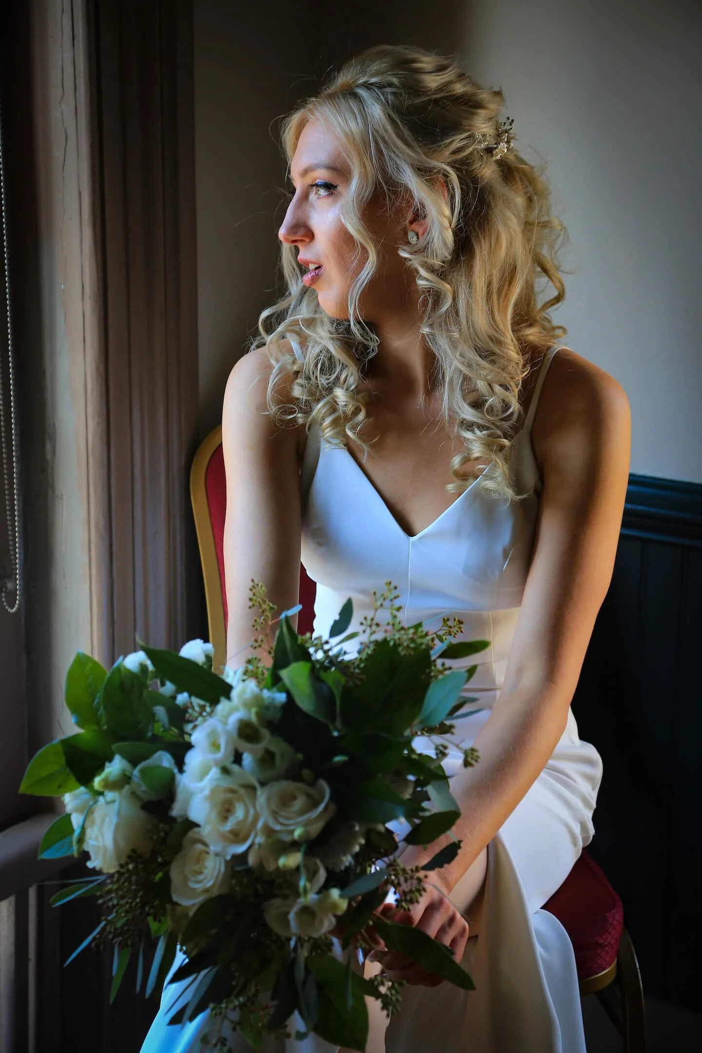 Bride staring out window with natural lighting