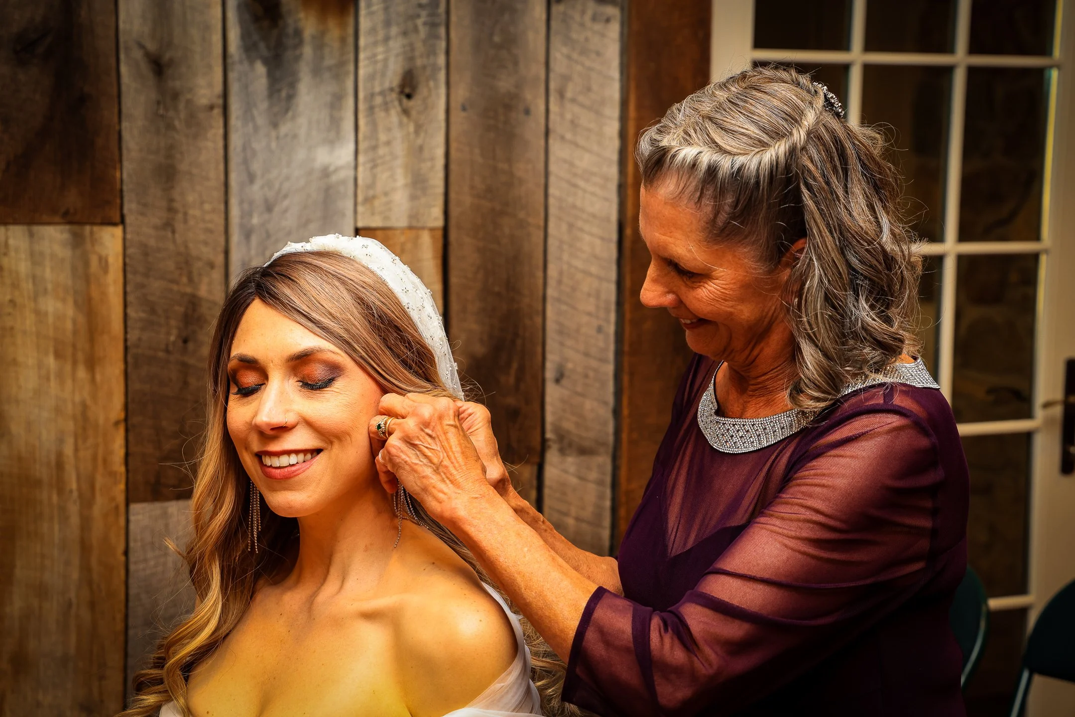 Bride and mother getting ready both smiling in a rustic setting showing natural skin tones | Whysall Photography