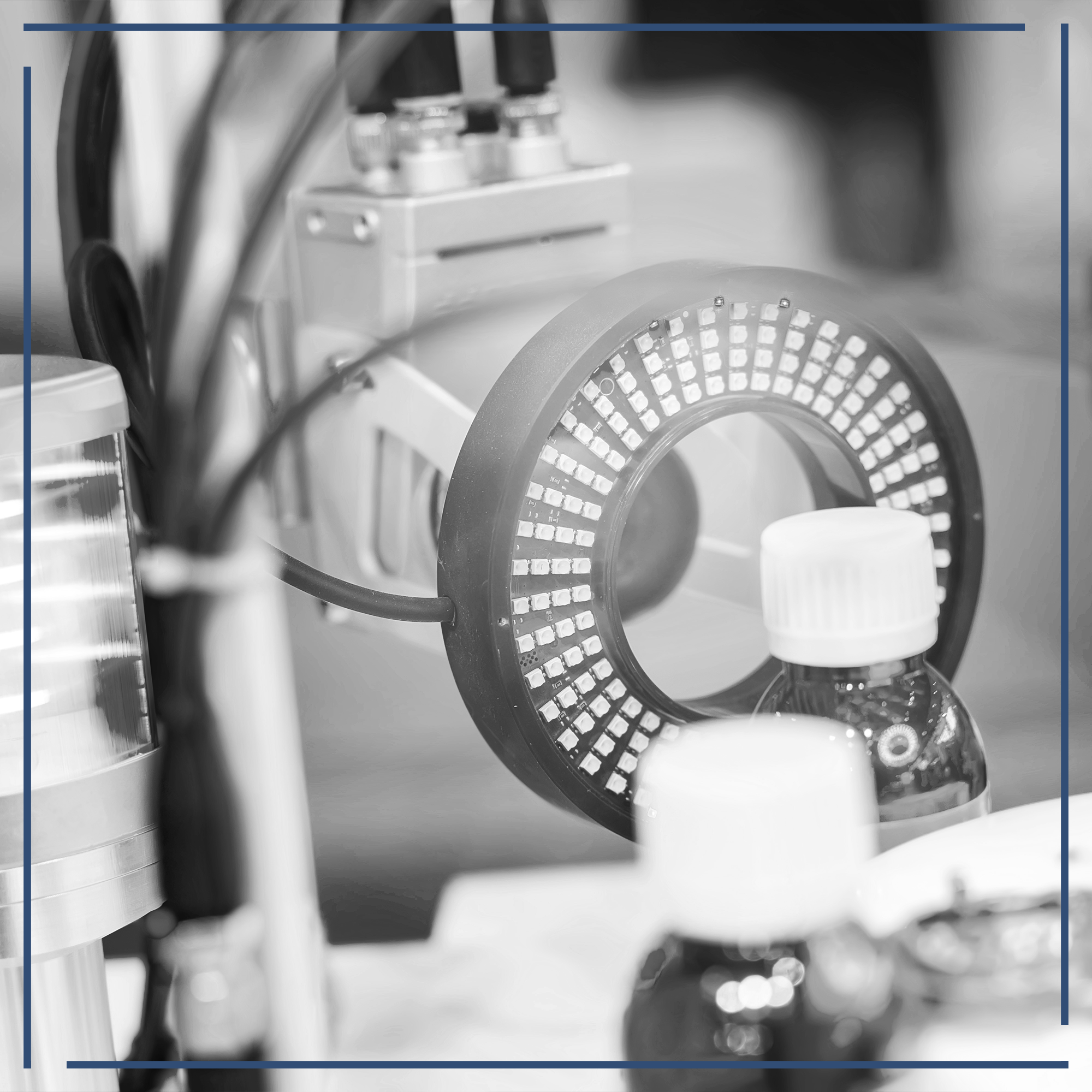 Nahaufnahme von technischen Geräten, einschließlich eines ringförmigen LED-Lichts, das auf eine Flasche mit Schraubverschluss gerichtet ist. Technologieumgebung, Focus auf Fertigungsprozess.