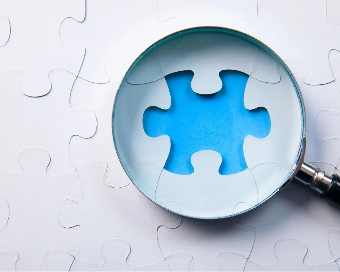 a magnifier glass highlighting a missing piece of a puzzle