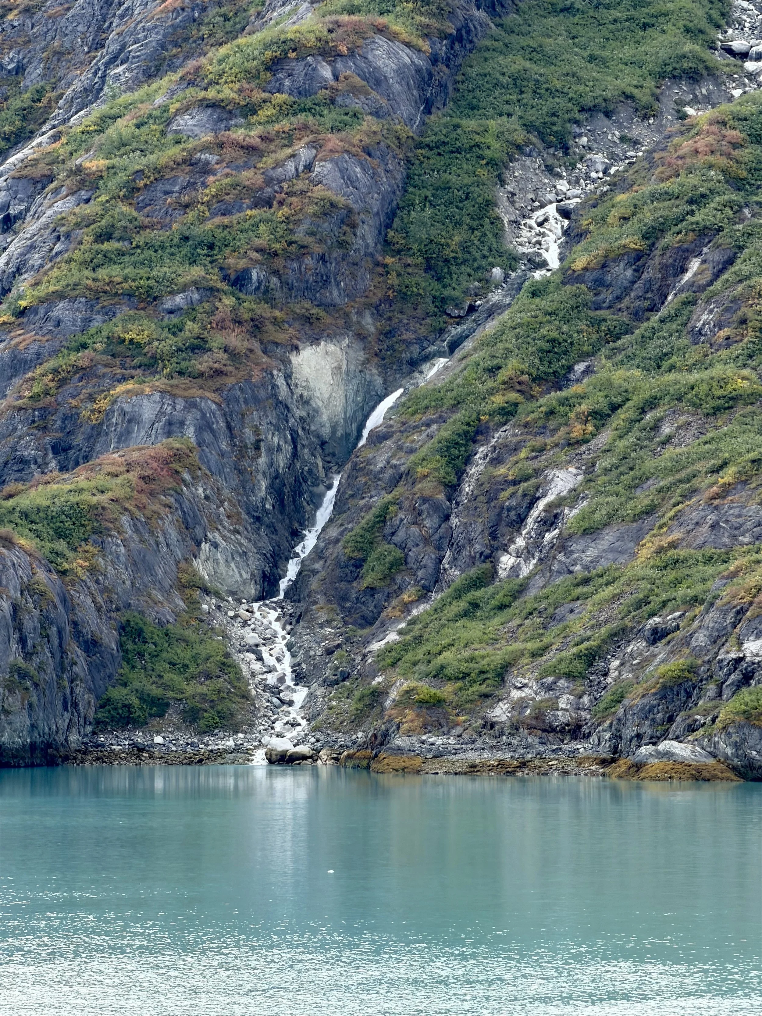  A waterfall cascading down the mountains at Glacier Bay National Park 