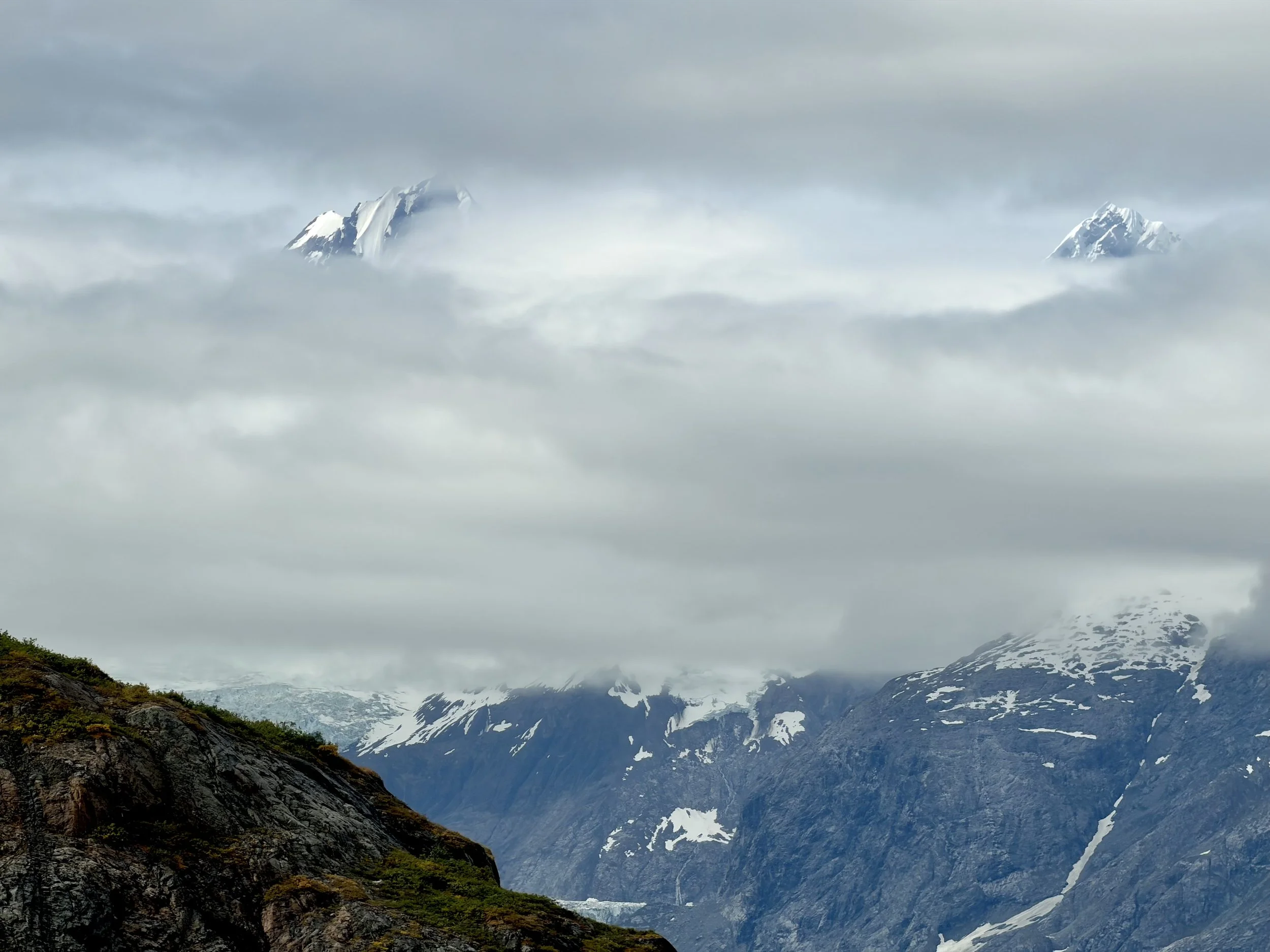  The tips of two mountains peaking through the low clouds at Glacier Bay National Park 