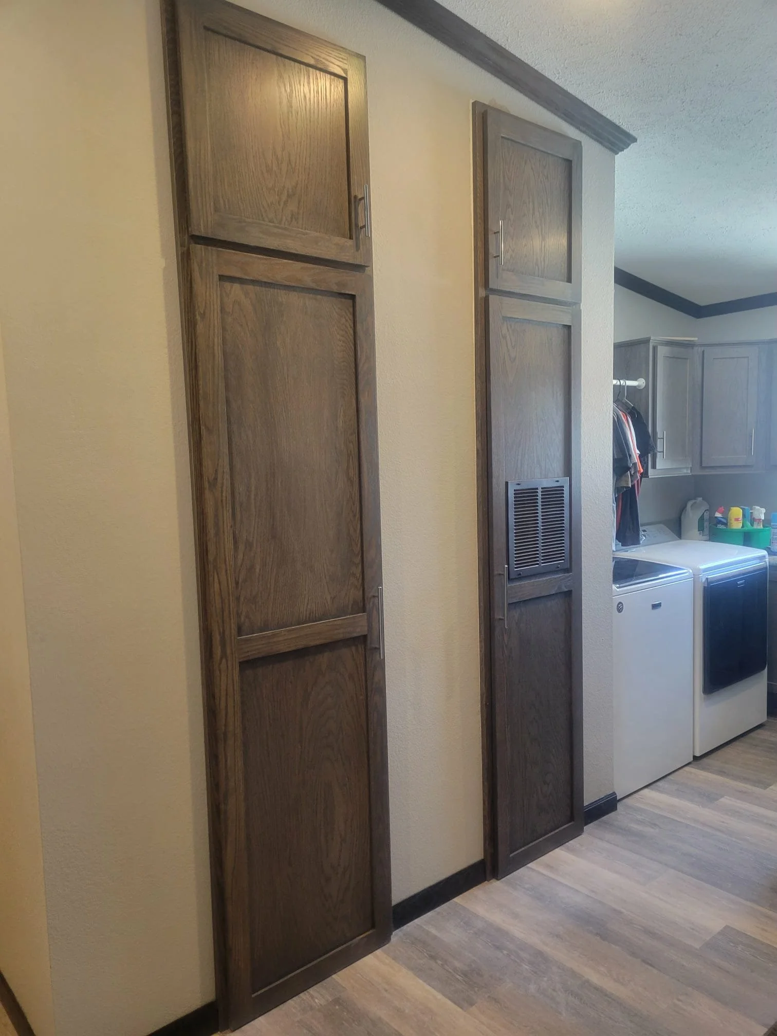Wooden cabinets with a vent cover on one, located in a laundry room with a washer and dryer visible.