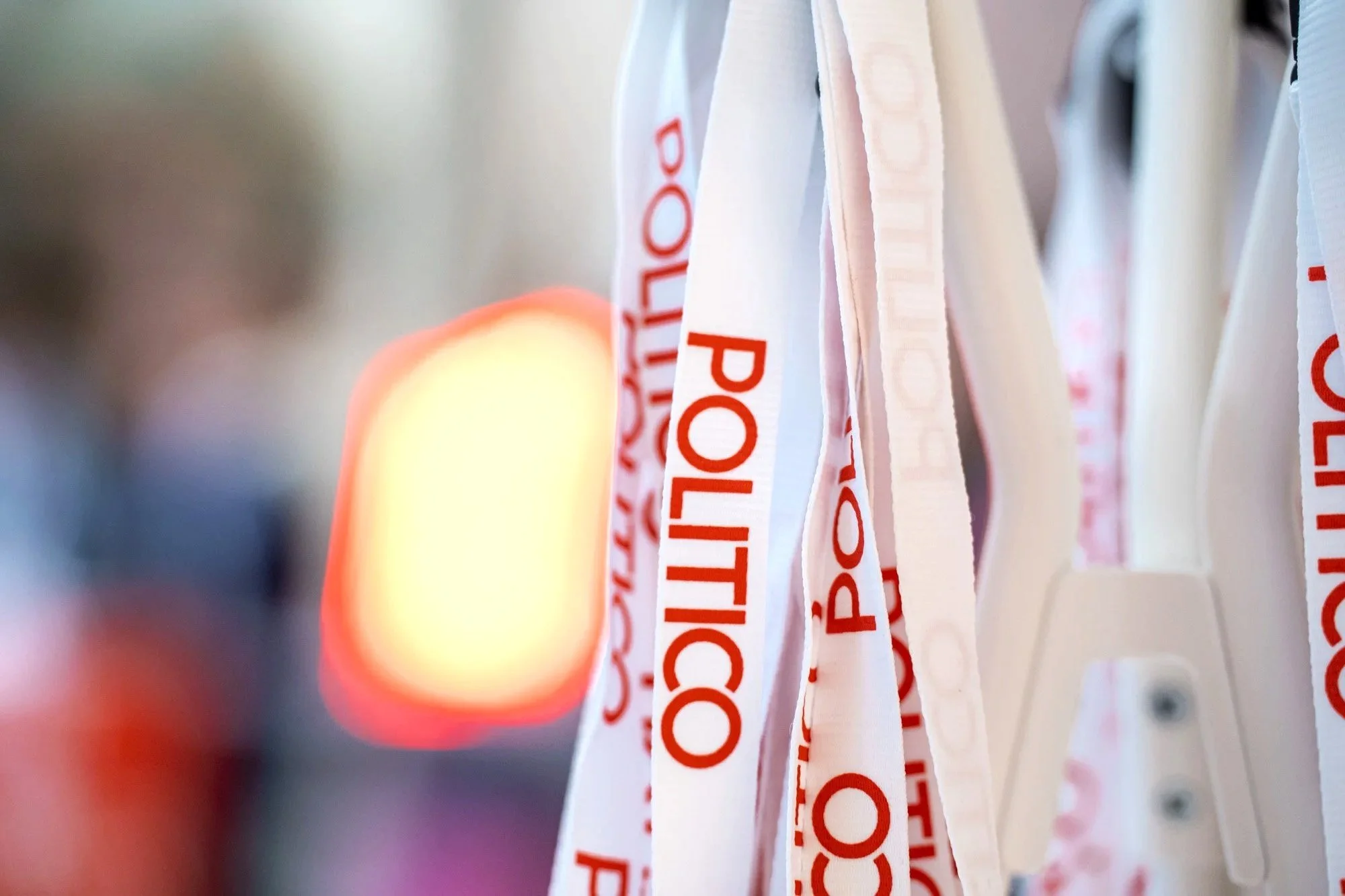 Close-up of hanging white ribbons with red text, possibly part of a display or decoration. Politico Event Photography Brussels.