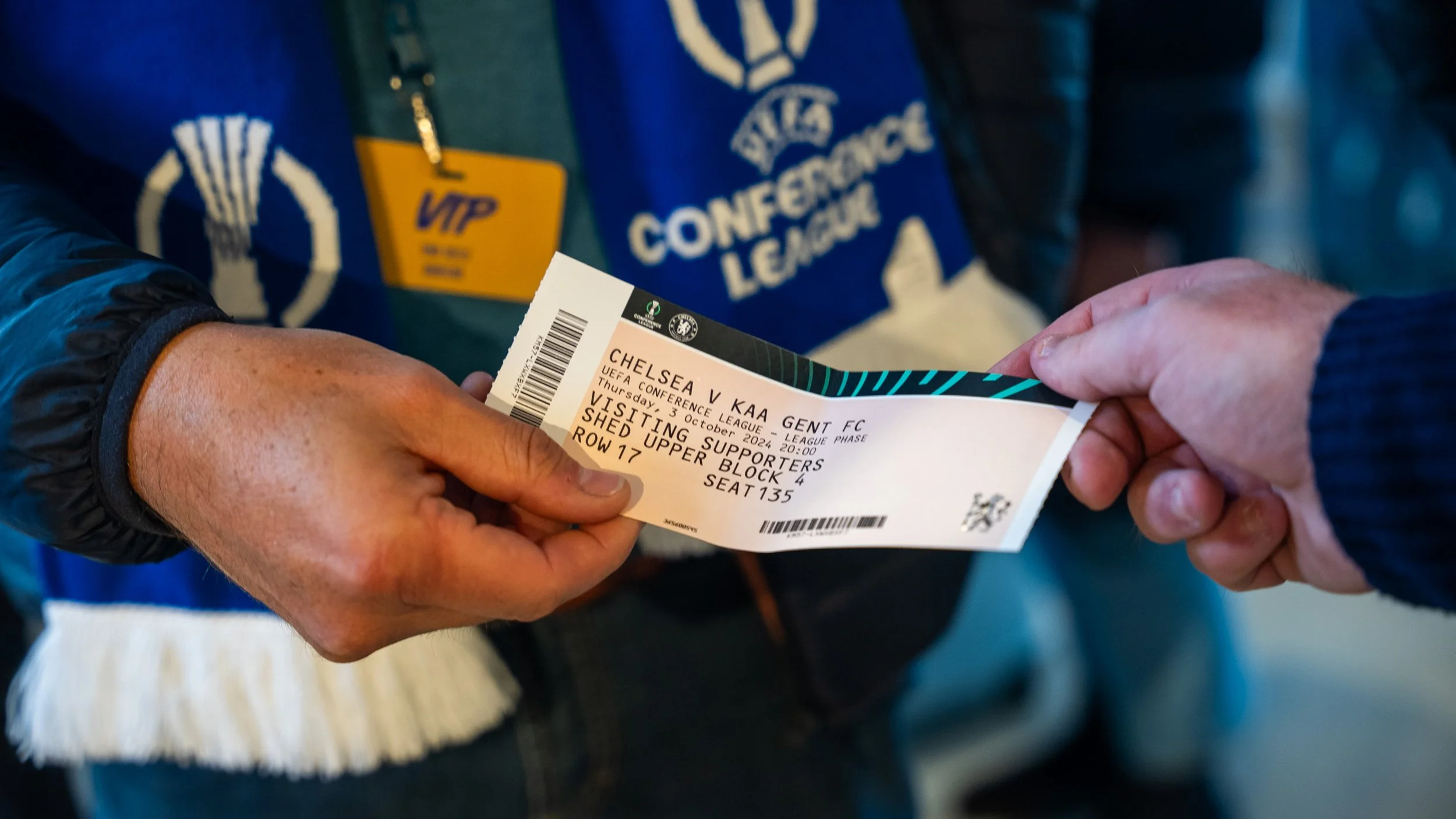 Close-up of a person holding a UEFA Champions League soccer match ticket for Chelsea versus KAA Gent FC, scheduled for October 3, 2024, at 21:00, at the Chelsea stadium, in row 17, seat 135, in the visiting supporters' upper block.