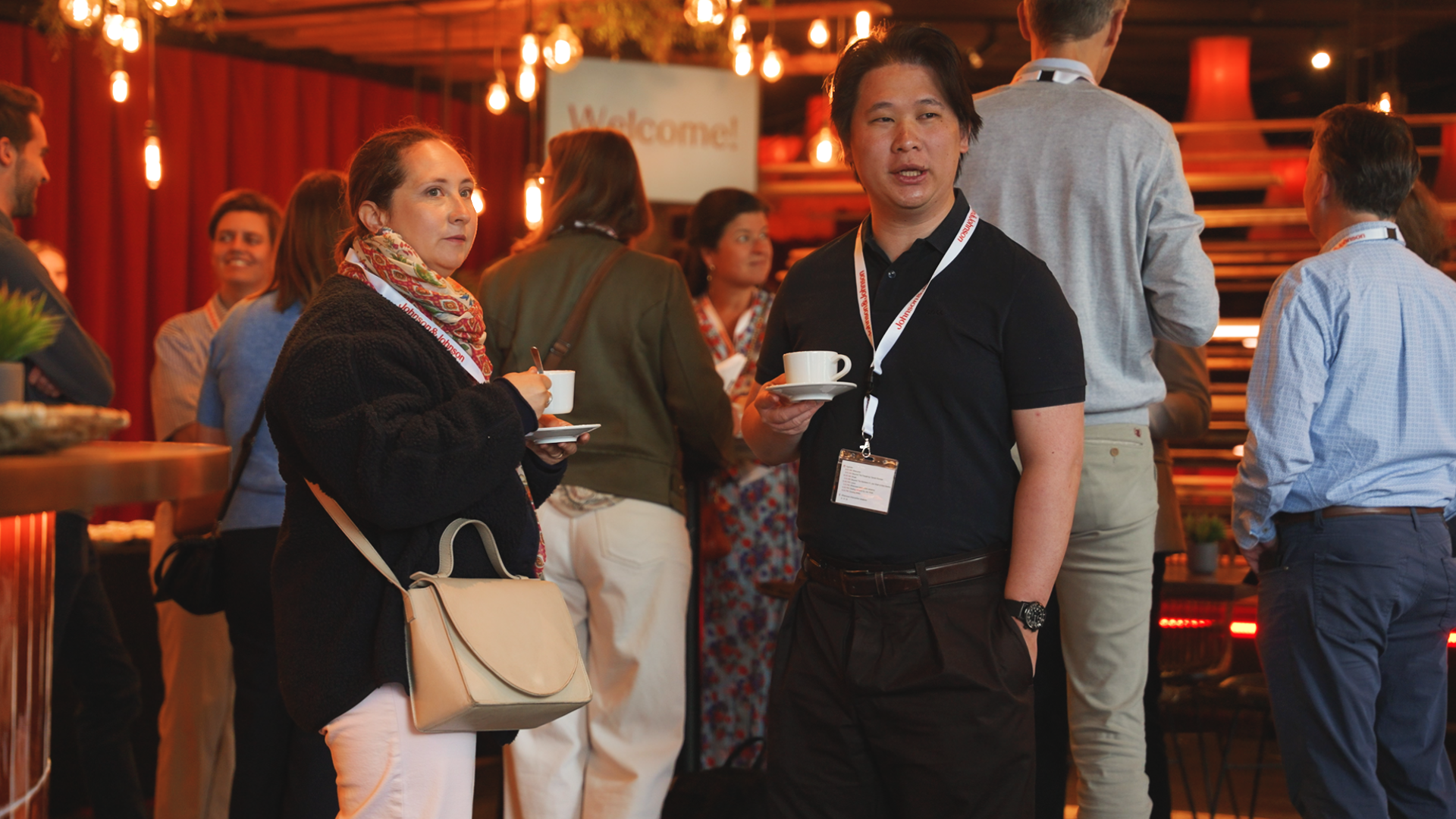 People at a networking event holding coffee cups and engaging in conversation, with warm ambient lighting and a welcoming atmosphere. johnson & Johnson Finance day 2026 at Tv studio Play Antwerp Zuid