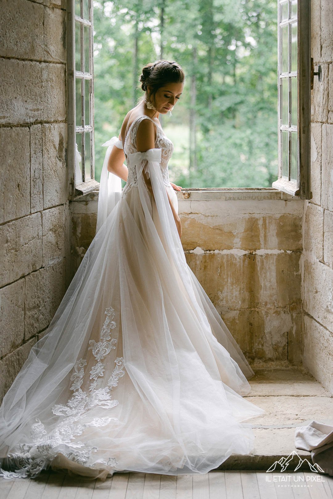 Mariée à la fenêtre avec sa magnifique robe