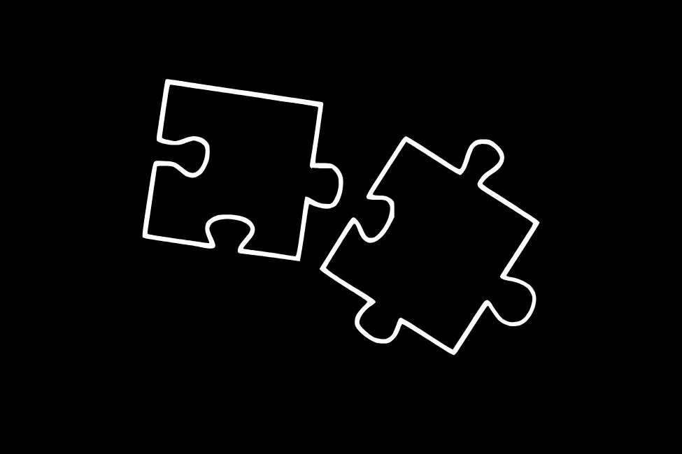 Two empty puzzle pieces, outlined in white, on a black background.