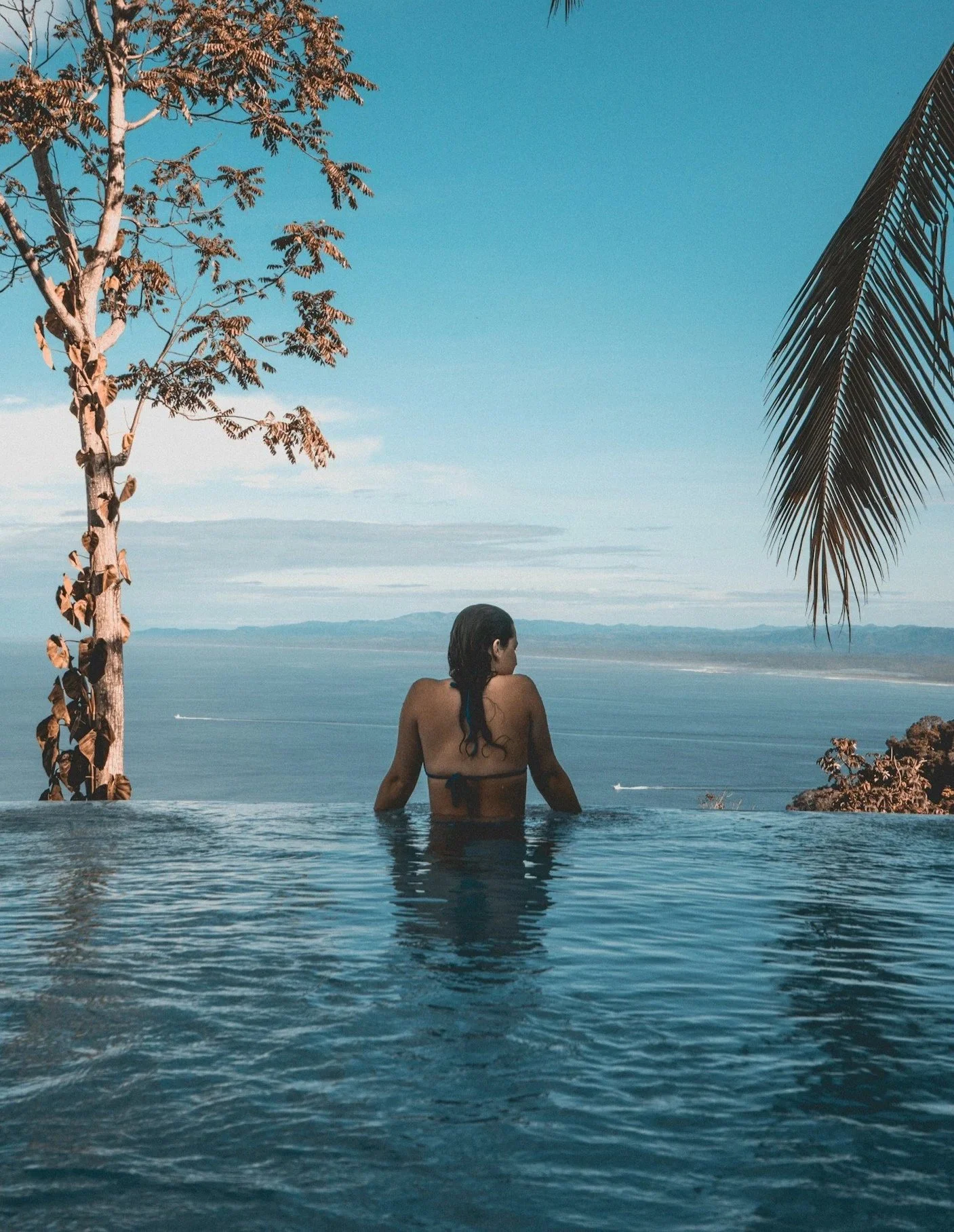 Woman relaxing in an infinity pool overlooking the sea.