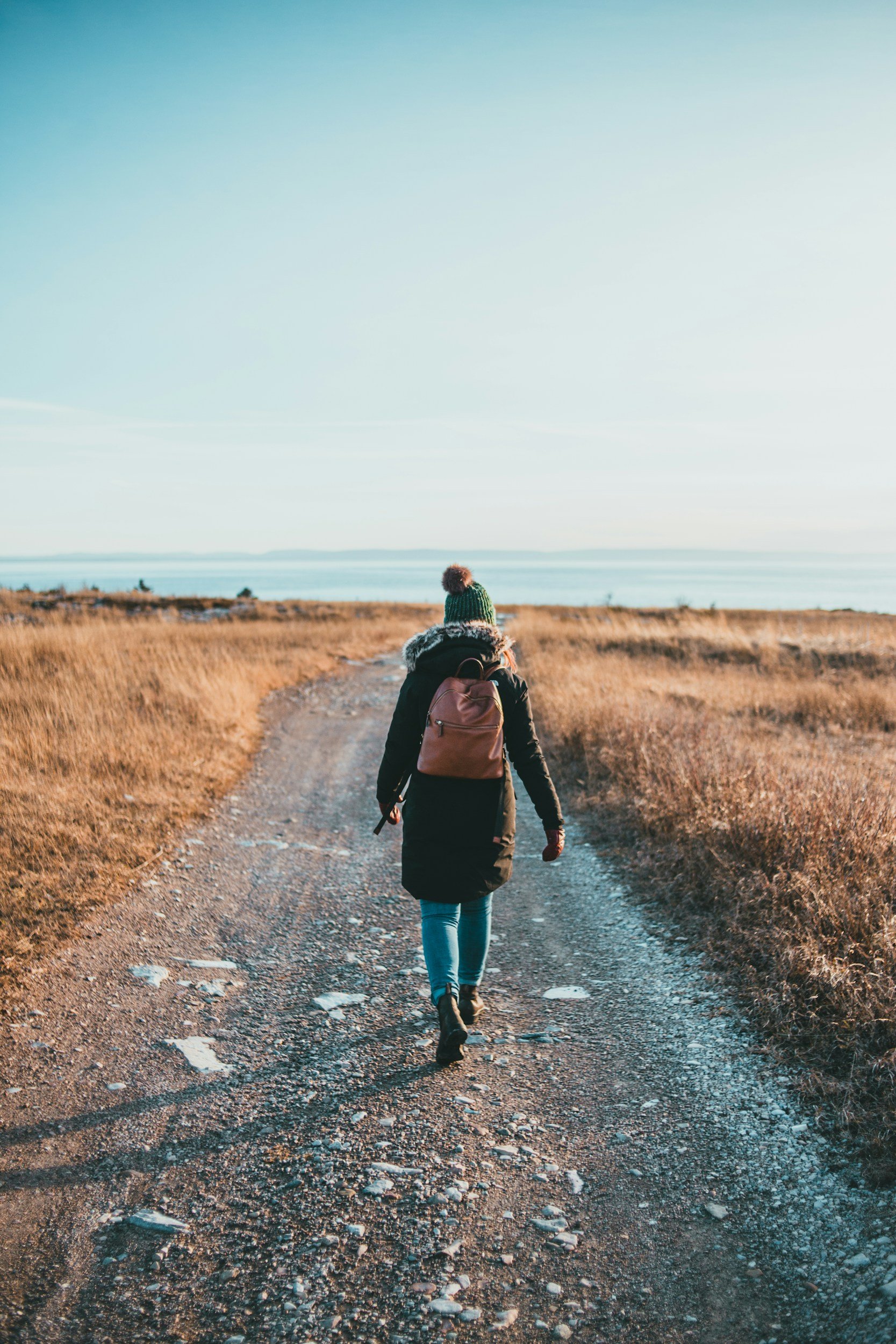 Woman walking along a path towards the sea, representing personal growth, change and a new chapter.