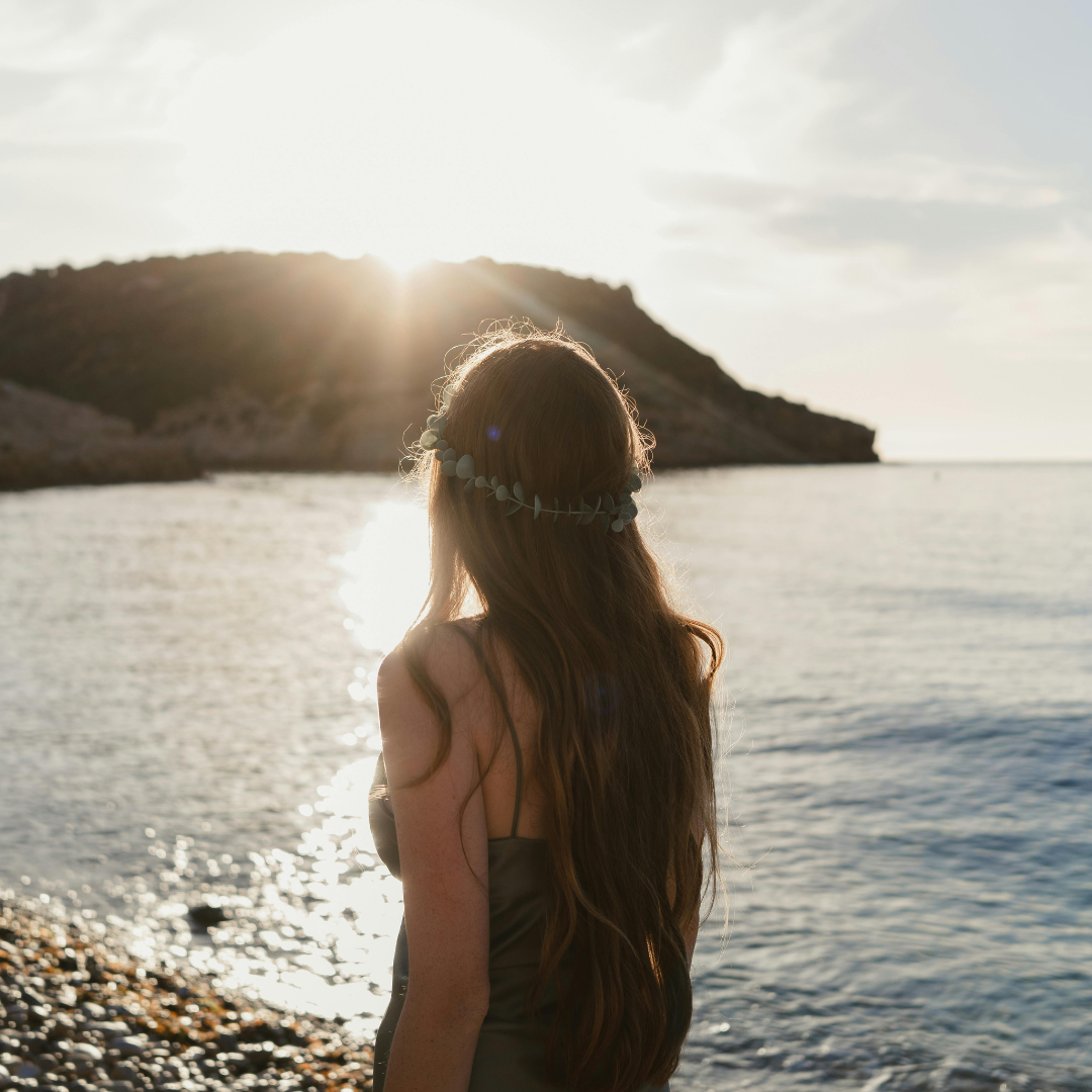 Woman walking beside the sea with flowers in her hair.