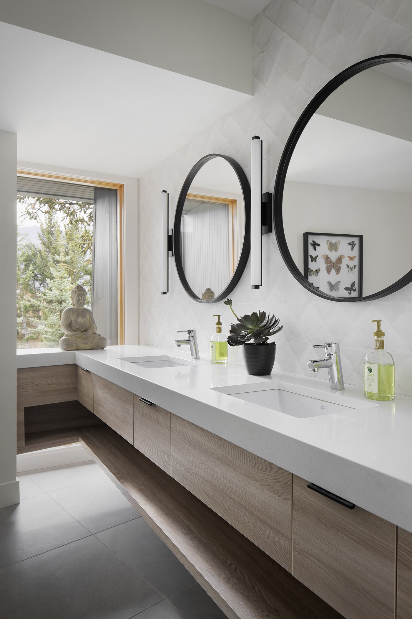 The vanity floats in front of a large window looking into the forest with a glimpse of the mountains.