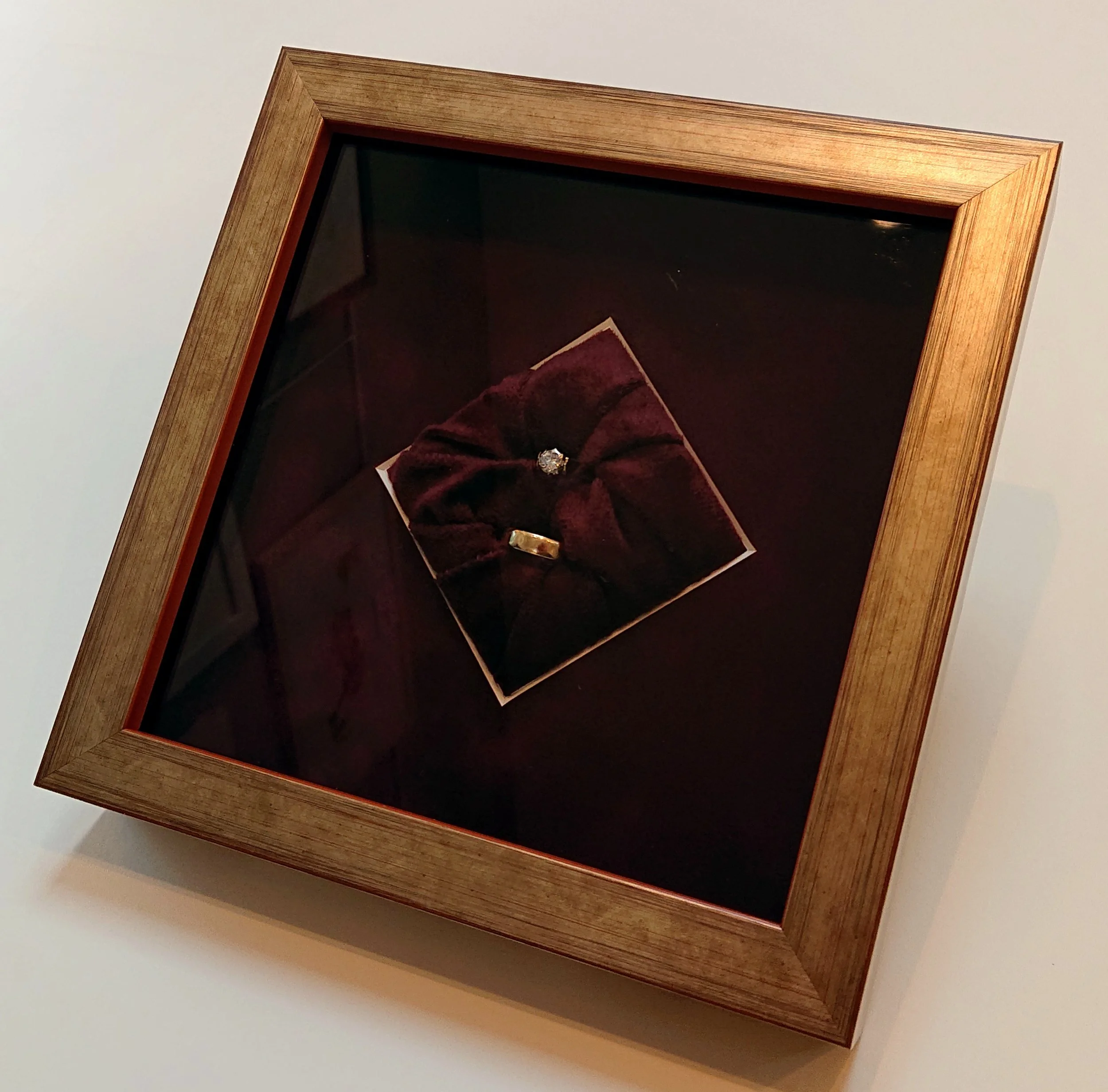 A wooden frame with a dark interior, possibly a display case, mounted on a white wall.