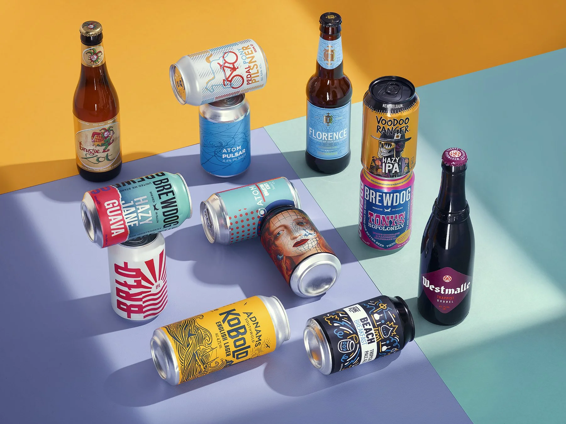 Various colorful craft beer cans and bottles arranged on a multicolored surface, featuring different labels and designs.
