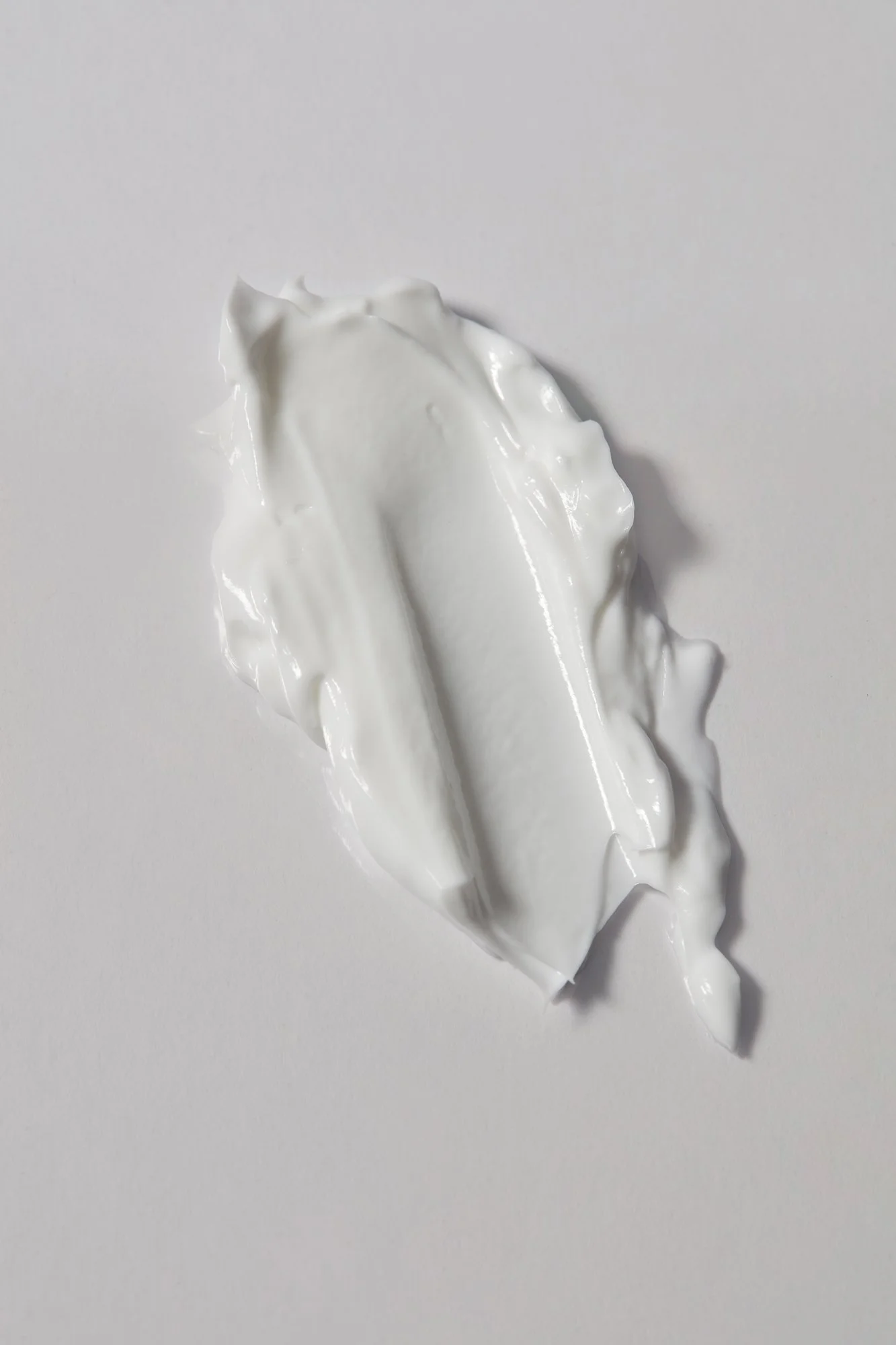 A dollop of white cream or lotion spread on a white surface.