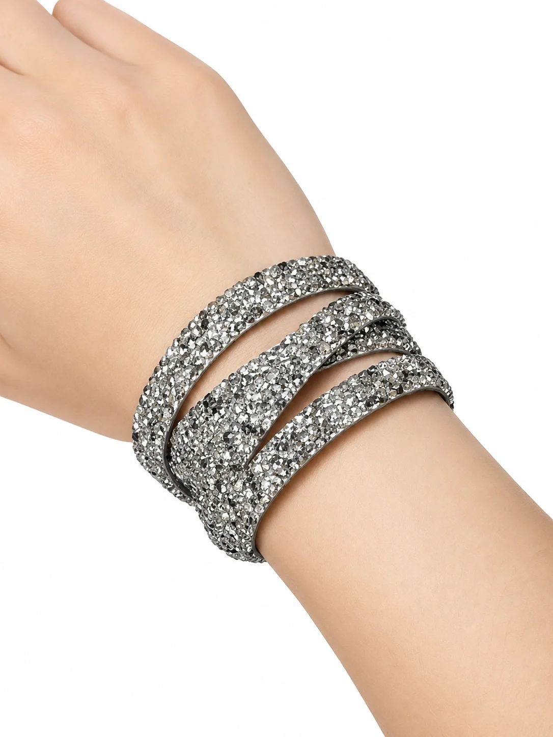 A person's arm wearing multiple silver glittery bracelets.