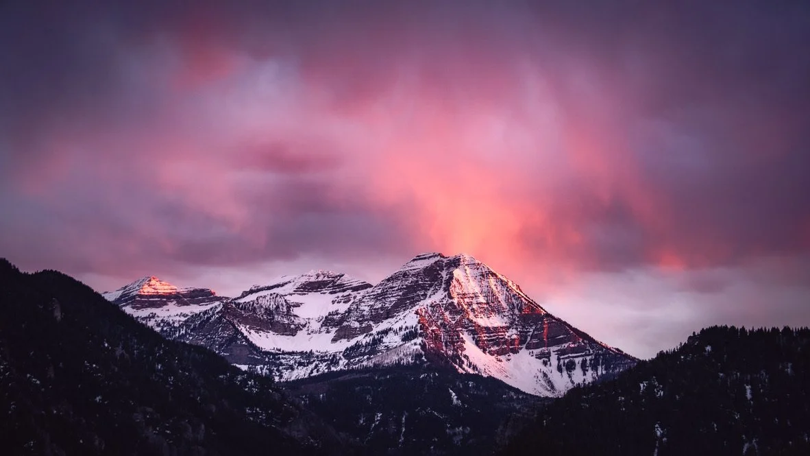 Snow-capped mountains under a colorful pink and purple sky at sunset