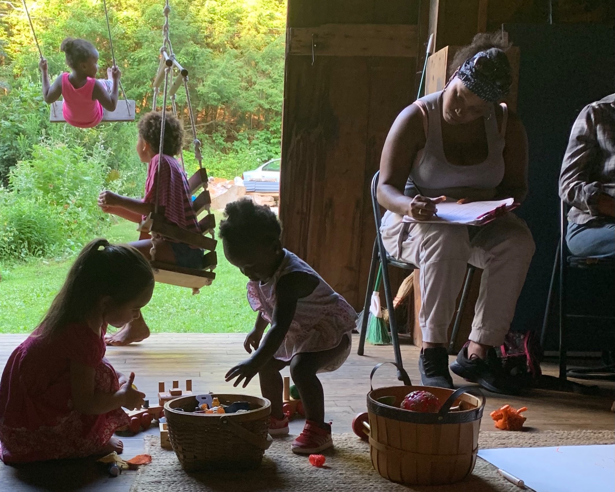 Beings gather in the community space, children playing with toys and on swings