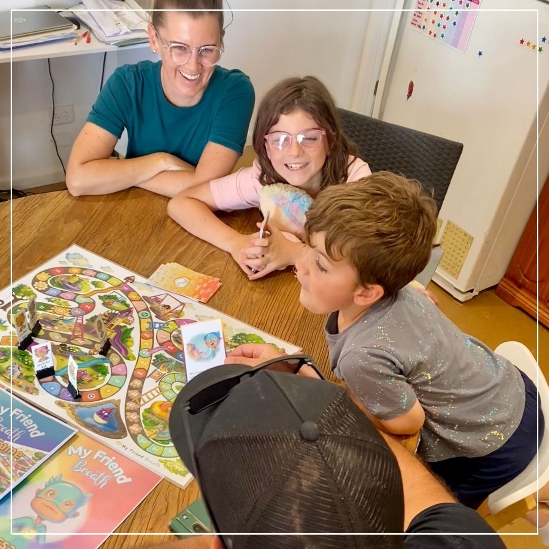 Mother, daughter, son, and father having fun practicing their mindful breathing by playing the My Friend Breath board game together at their dining table