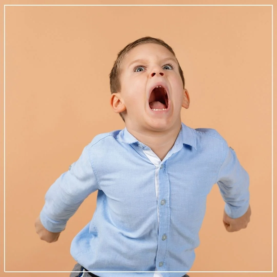 Young caucasian boy screaming in anger with hands balled into fists extended behind him.