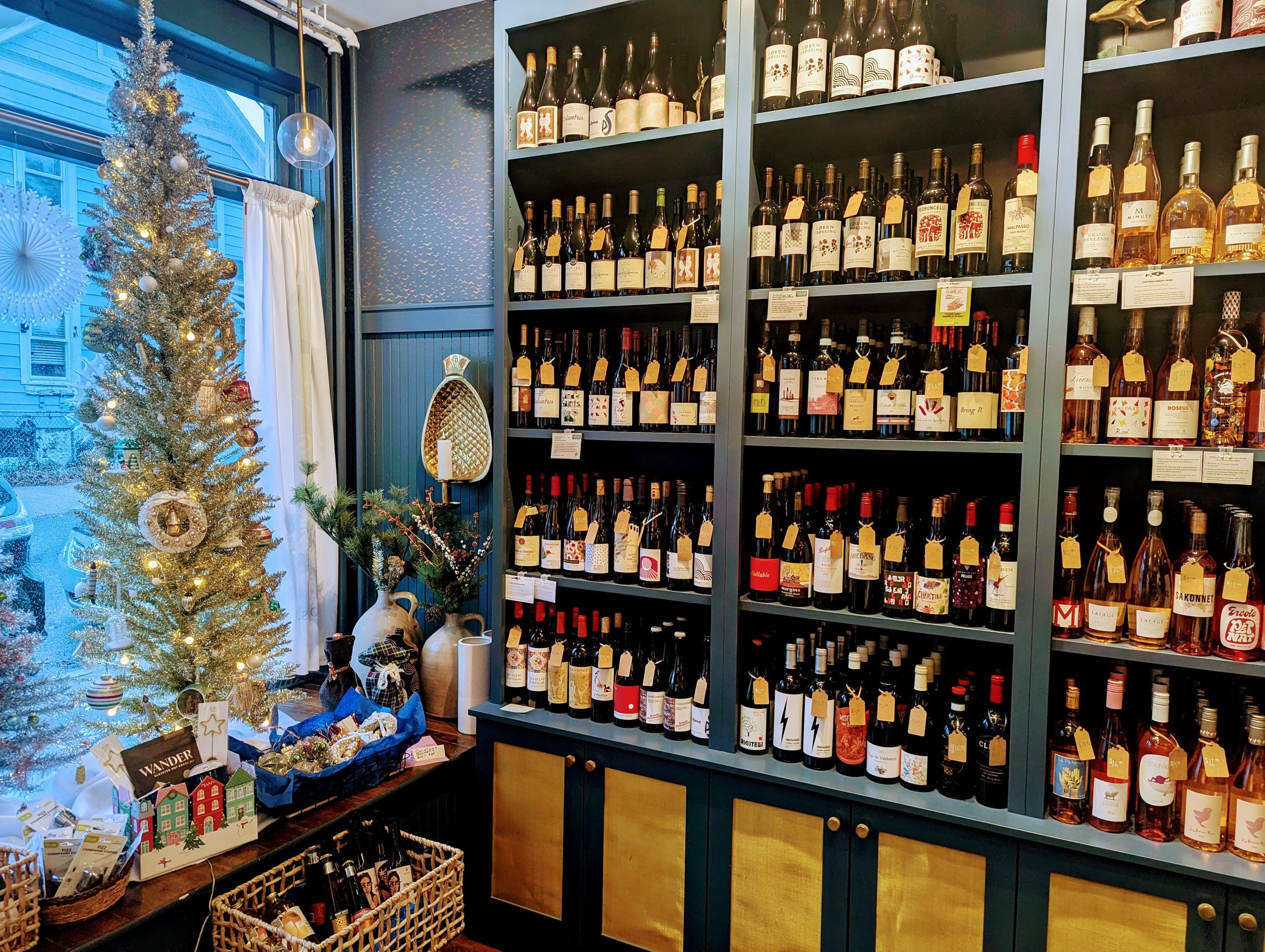 Christmas decorated store with a small Christmas tree, shelves of wine bottles, and holiday decorations.