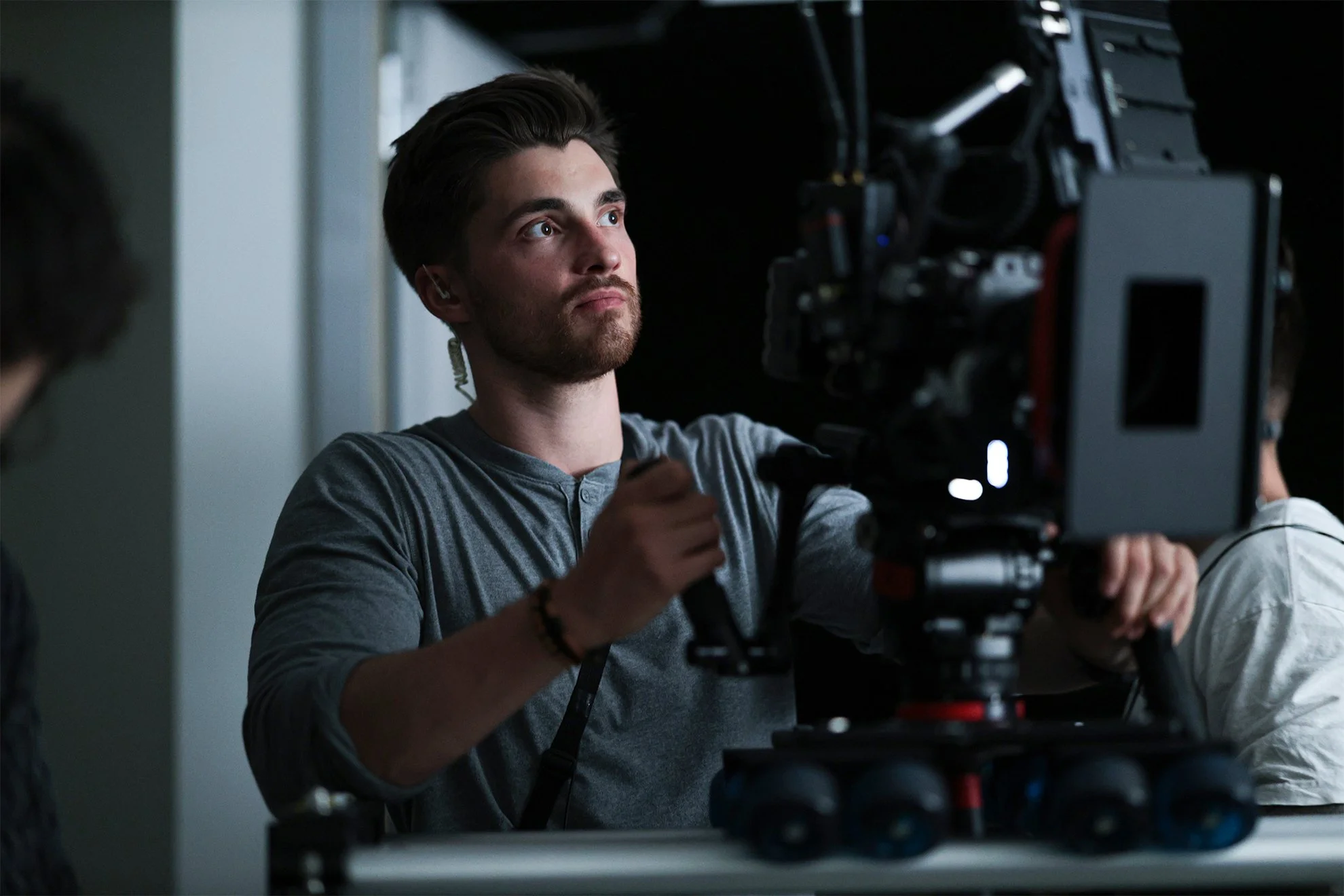 Cinematographer operating a cinema camera mounted on a slider in an indoor filming environment.