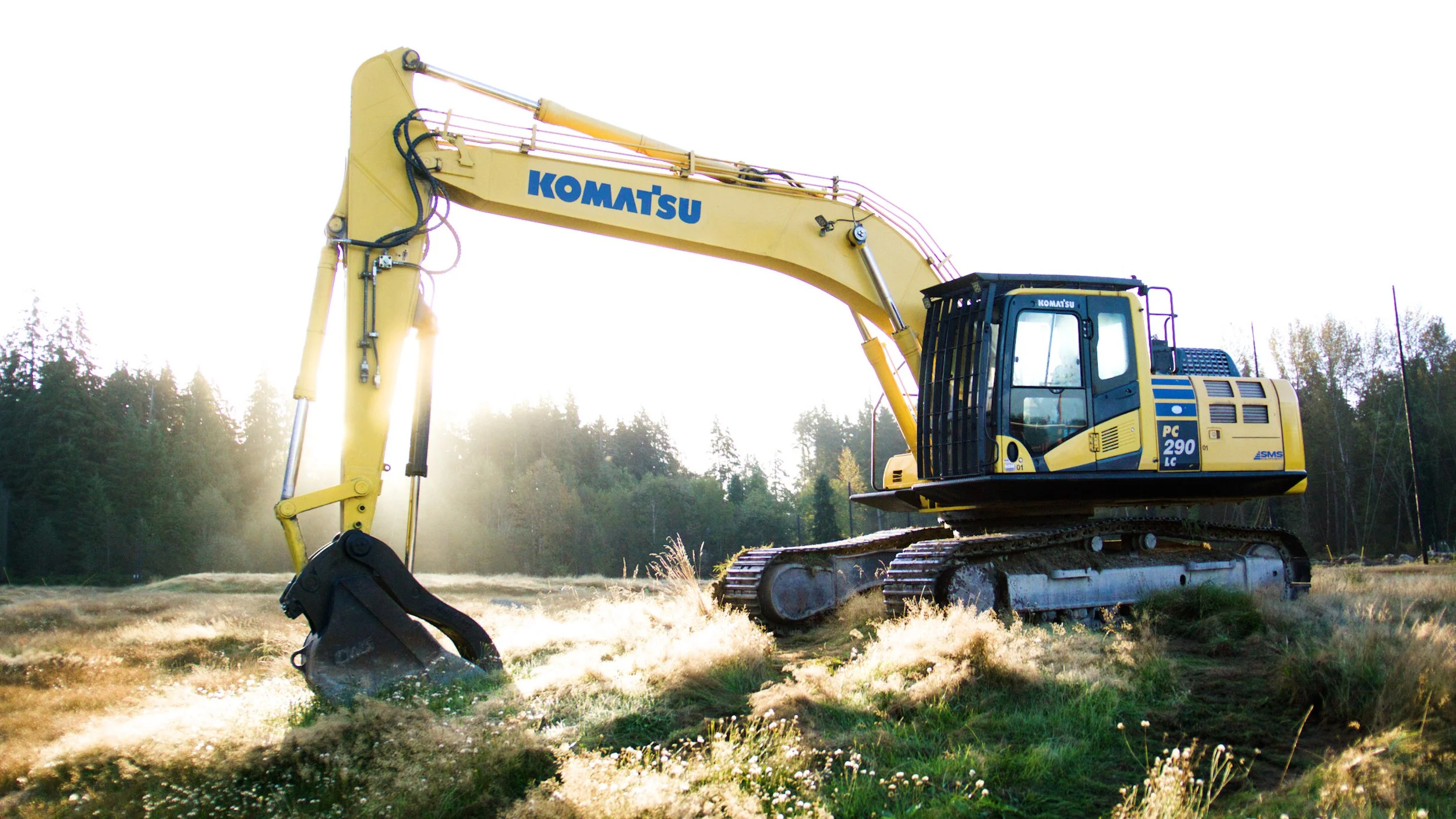 Komatsu excavator positioned at an outdoor demolition site in early morning light.