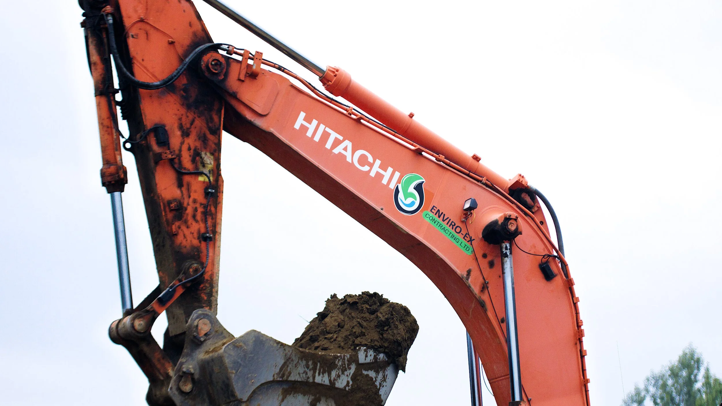 Close-up of a Hitachi excavator arm lifting soil at a construction site.