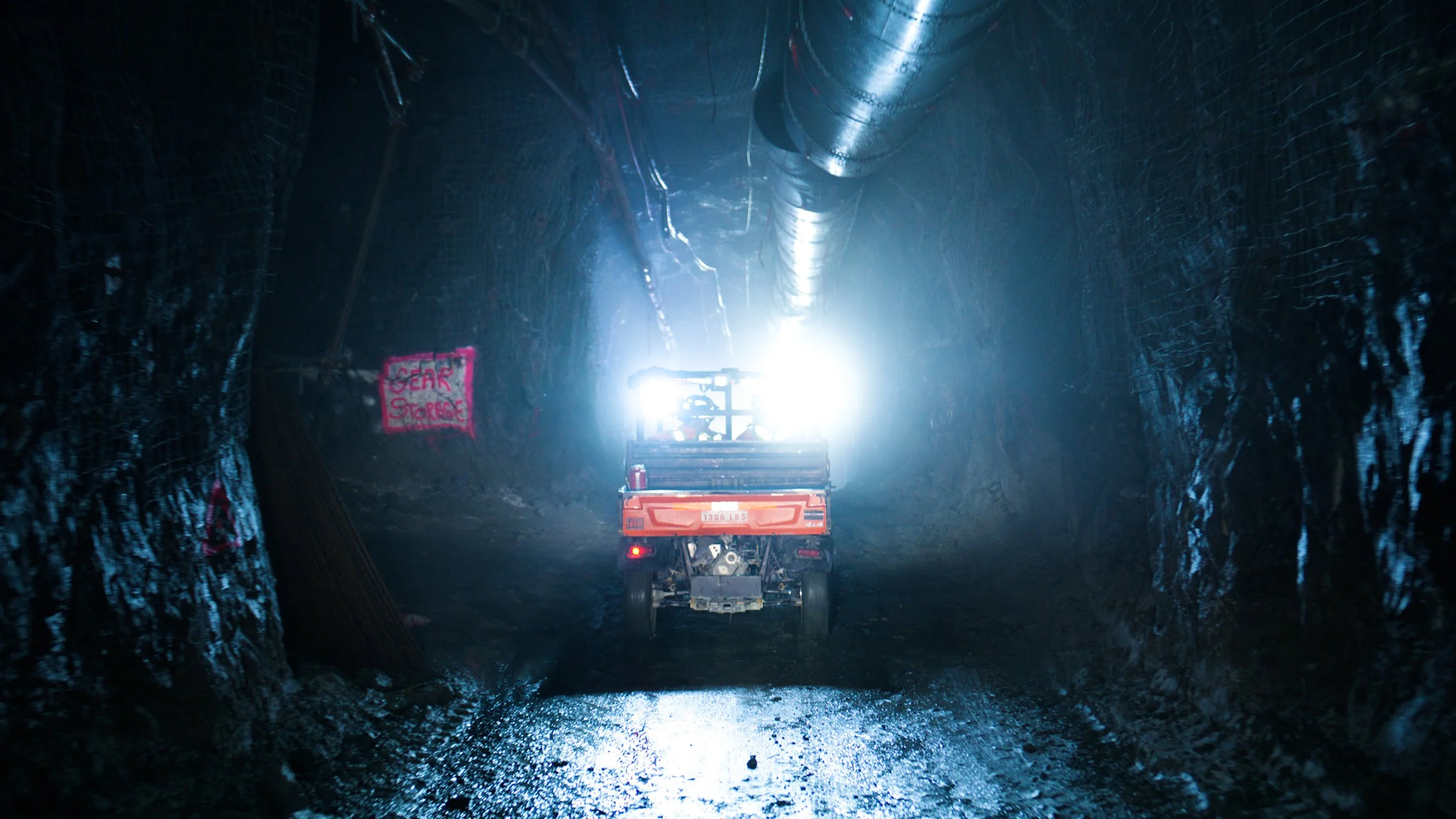 Utility vehicle driving through an underground tunnel inside a gold mine.