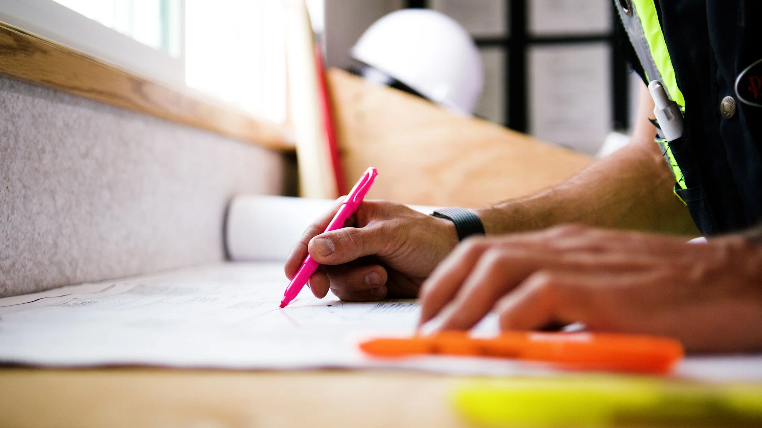Close-up of construction professional marking building plans with a highlighter.