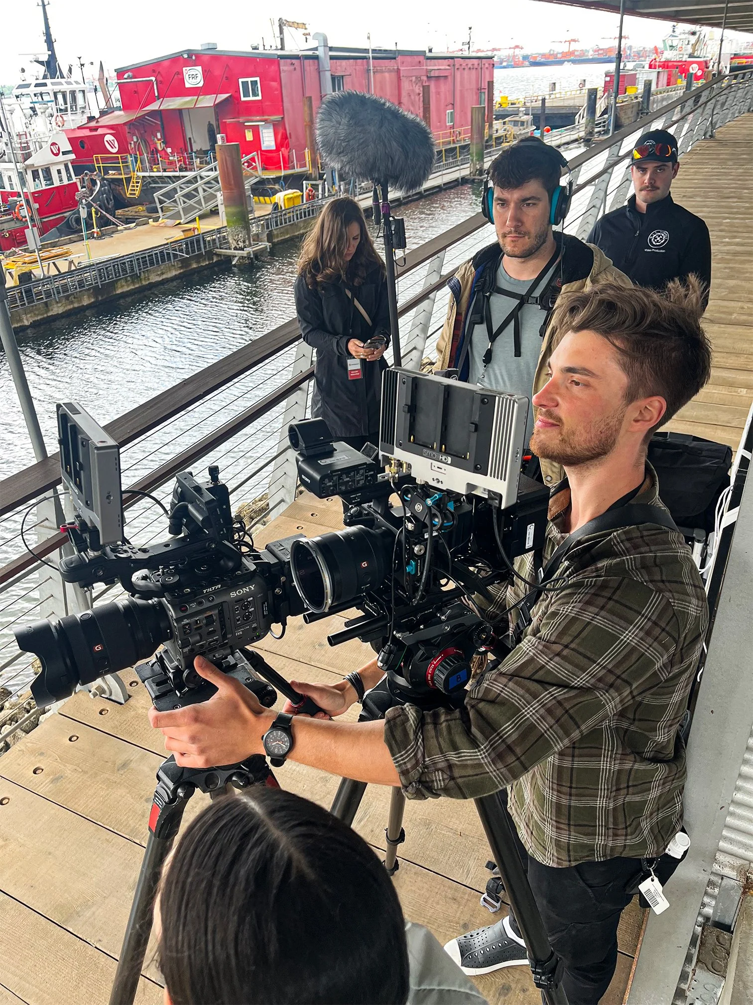 Cinematographer operating dual cinema cameras on tripods during an outdoor waterfront video production.