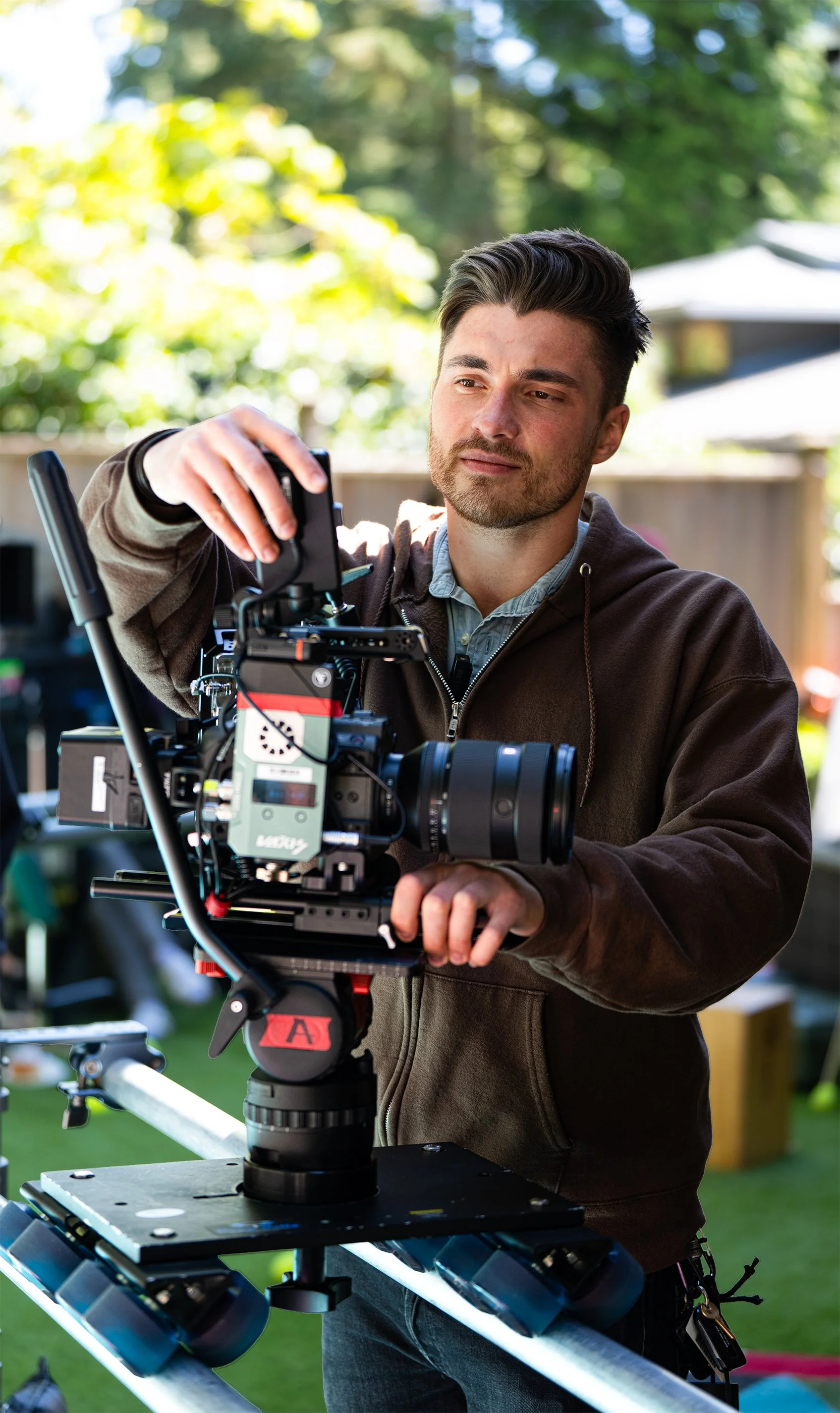 Cinematographer adjusting a cinema camera mounted on a slider during an outdoor video production.