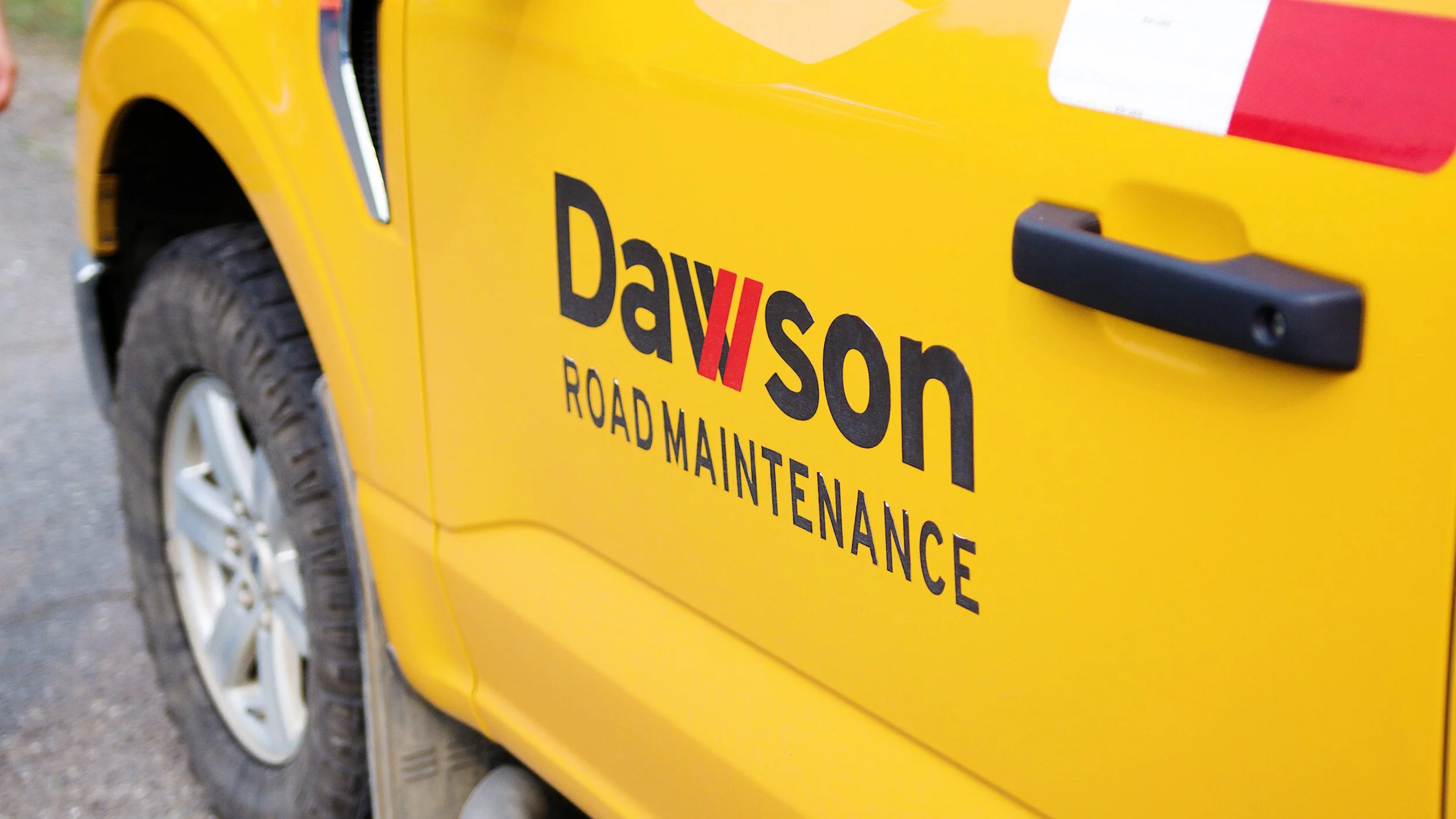 Dawson Road Maintenance logo on the side of a yellow service truck.