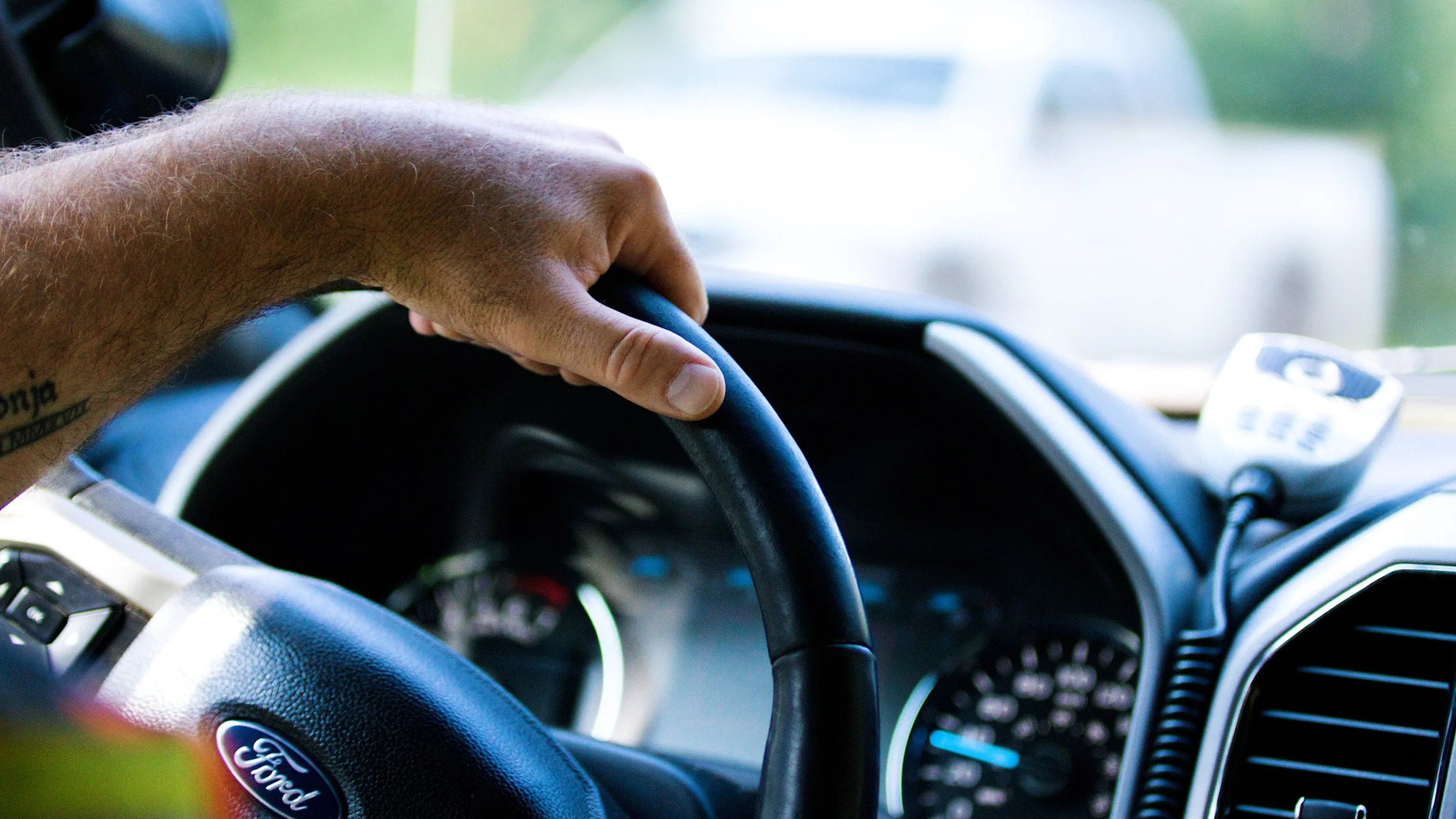 Close-up of a road maintenance worker’s hand on the steering wheel of a service truck.